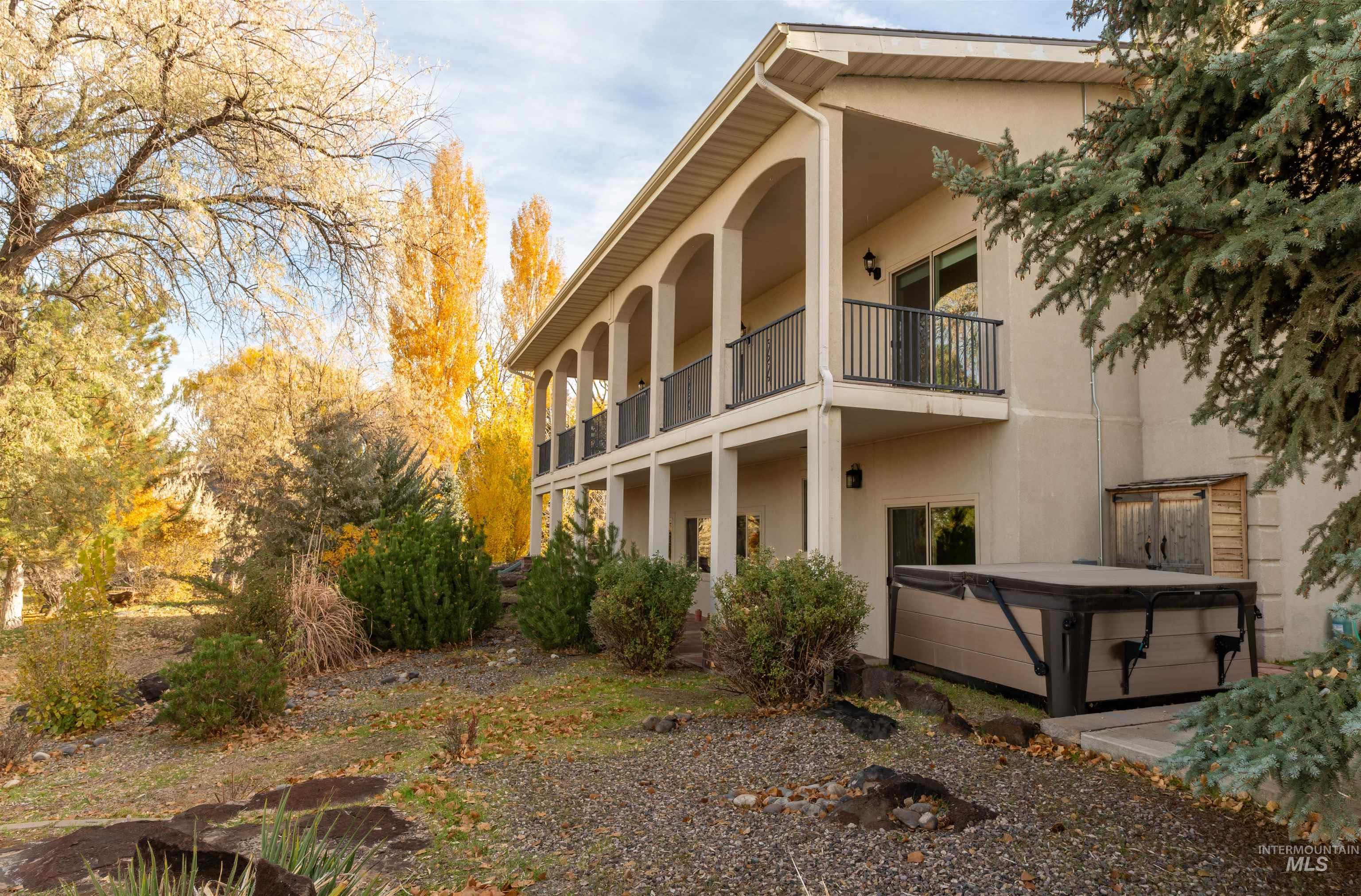 Back of house featuring a hot tub, stucco siding, and a balcony