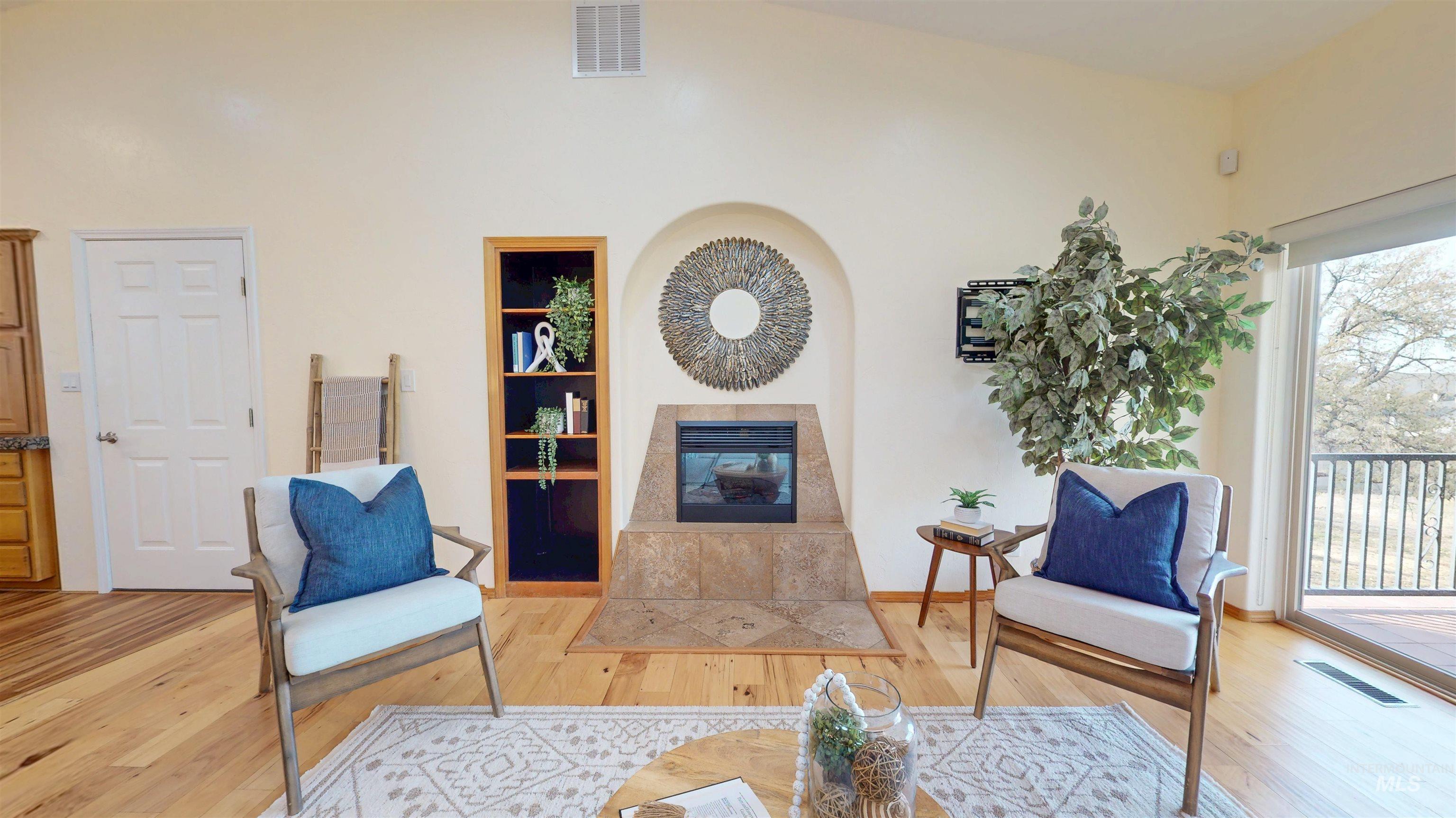 Great room with a tile fireplace, wood finished floors, and a high ceiling