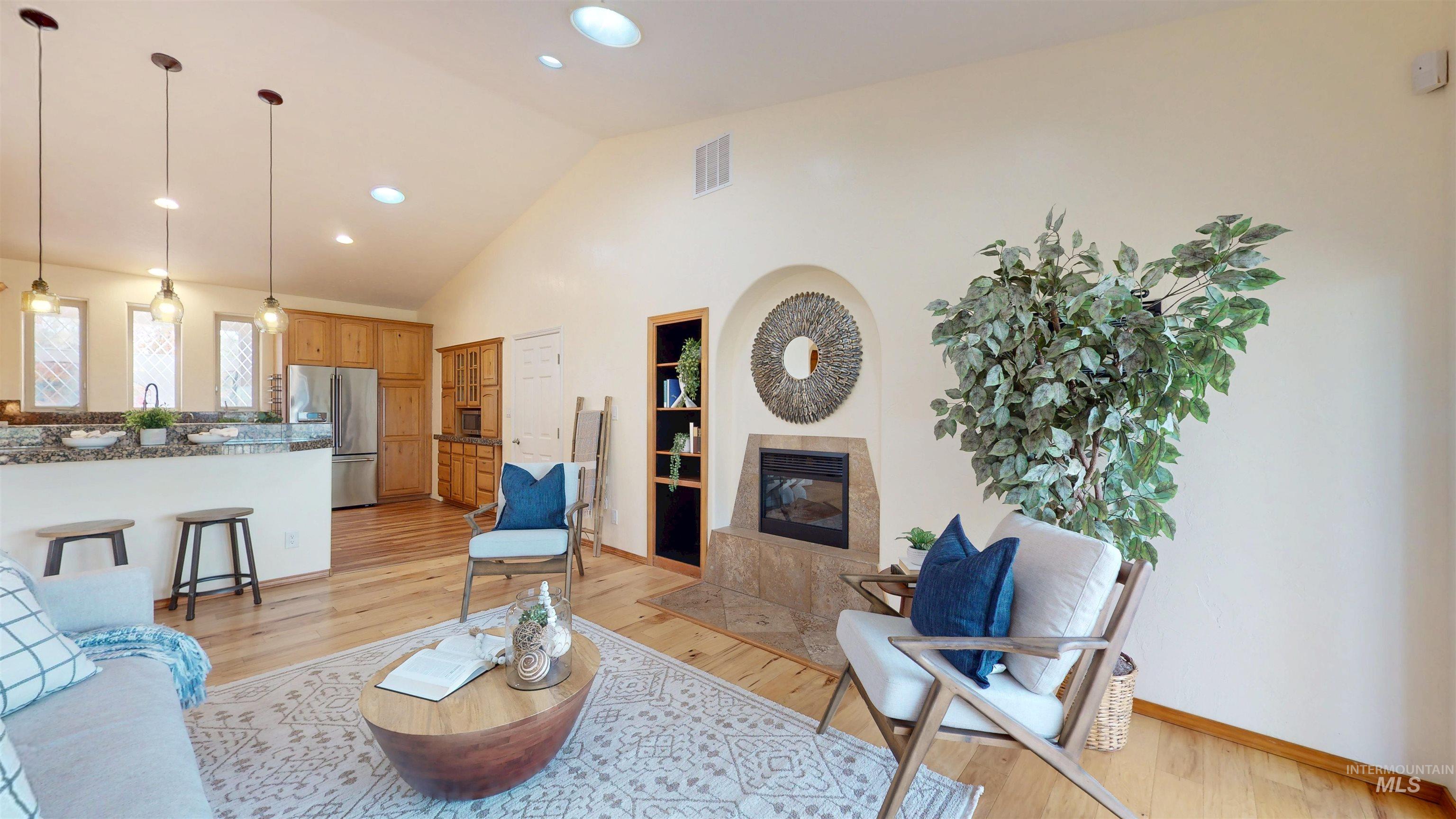Great room featuring light wood finished floors, a high end fireplace, high vaulted ceiling, and recessed lighting