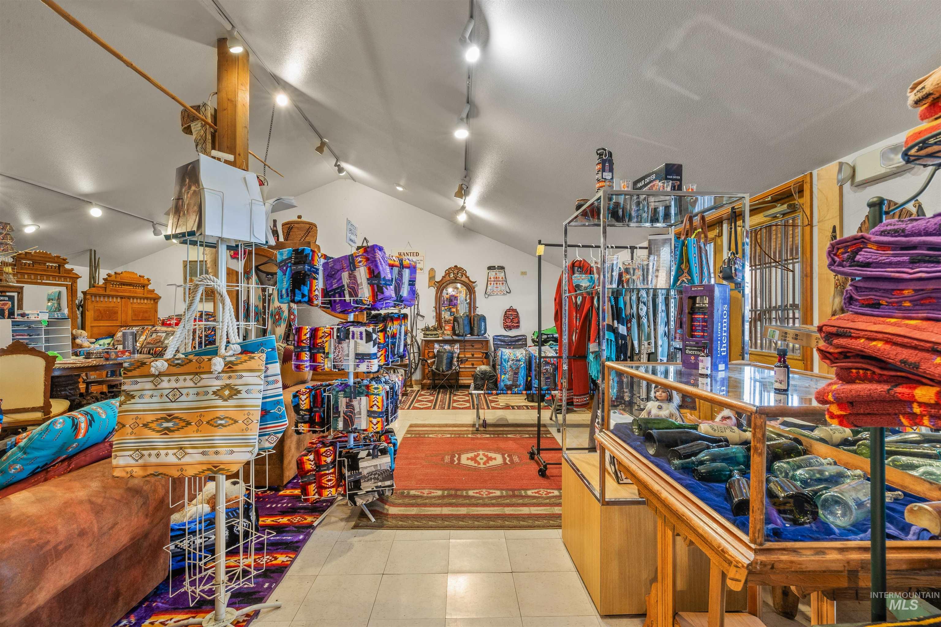 Miscellaneous room featuring light tile patterned floors, rail lighting, and lofted ceiling