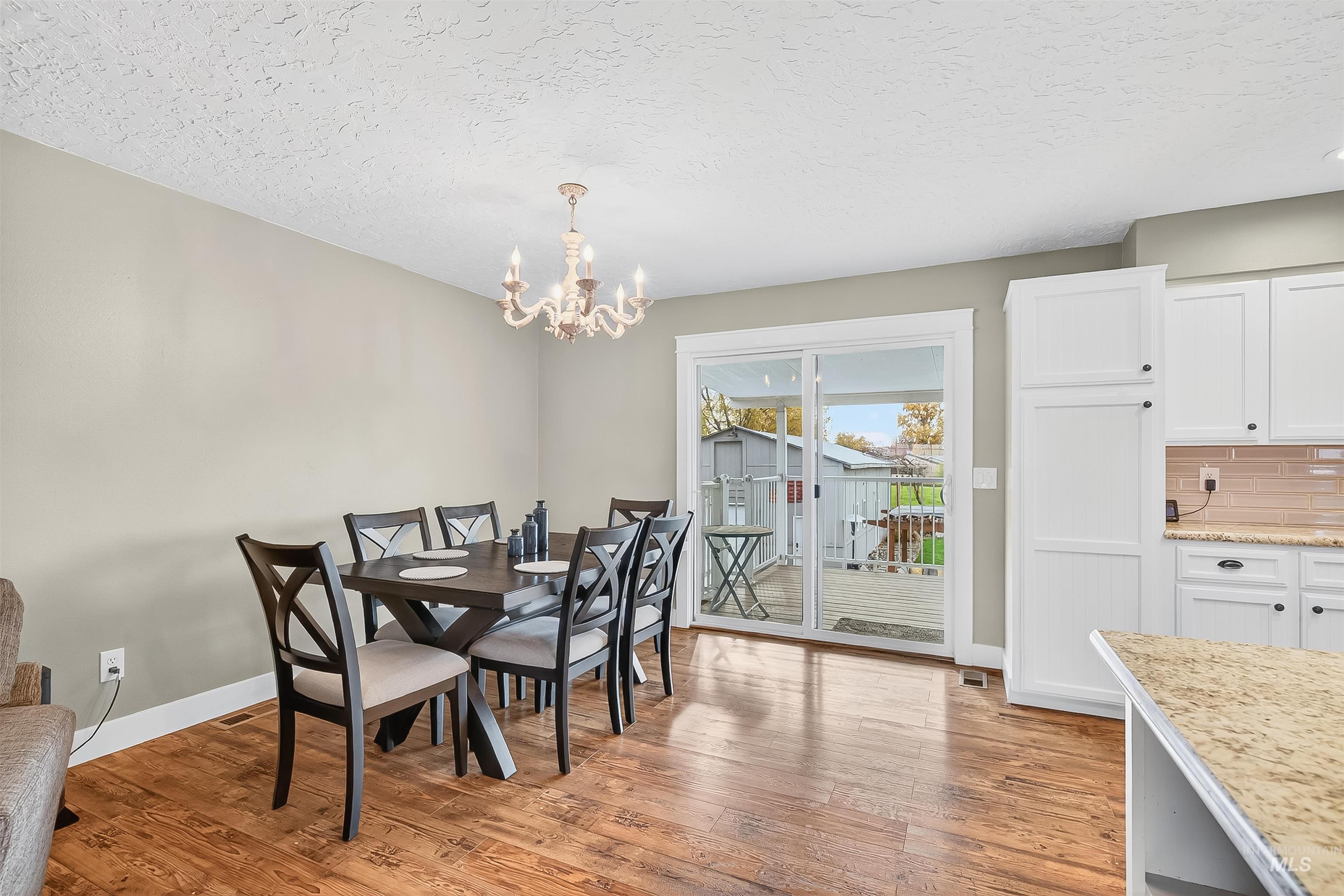 Dining room featuring light wood-type flooring, a textured ceiling, and a chandelier