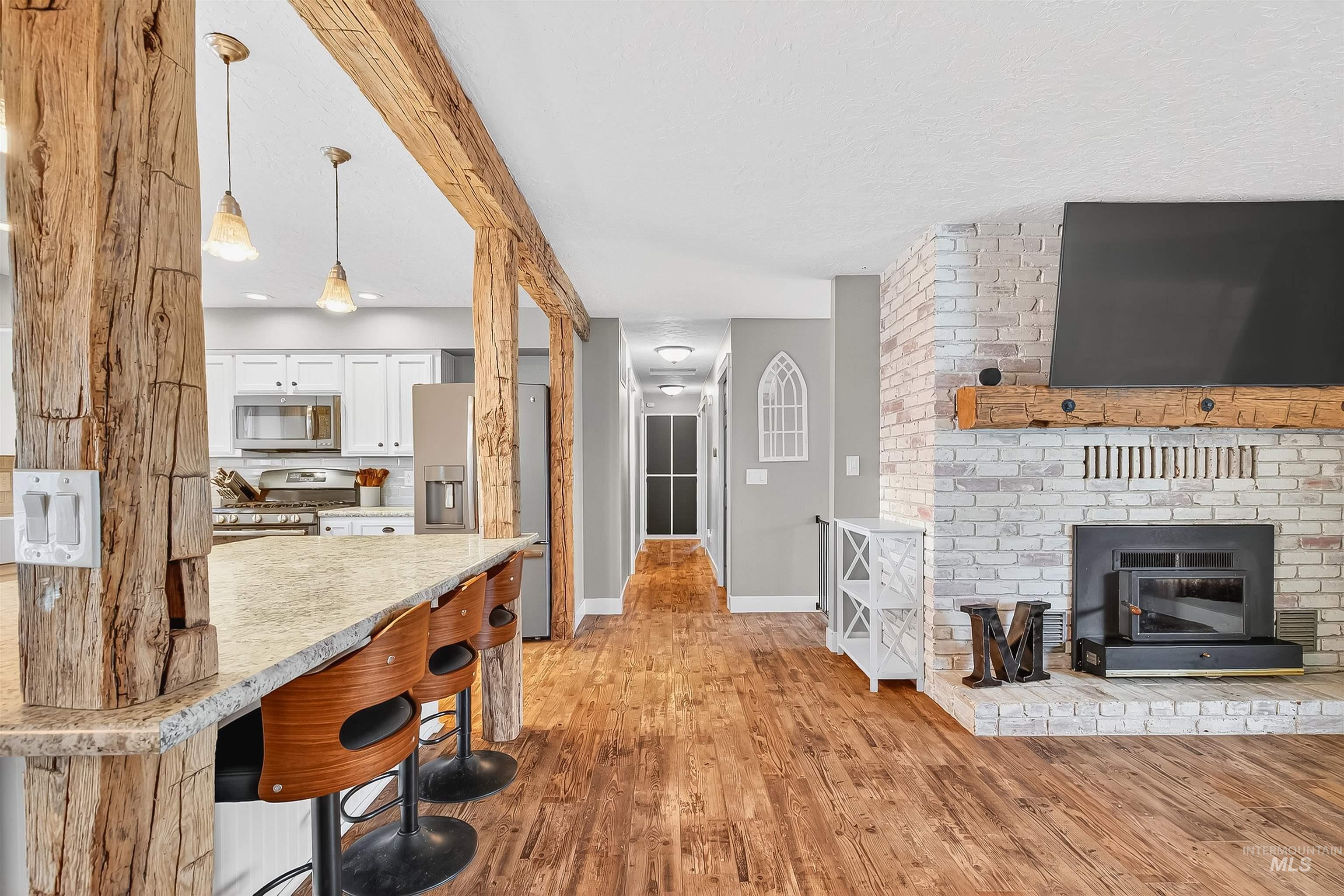 Kitchen featuring pendant lighting, light wood-style flooring, appliances with stainless steel finishes, white cabinetry, and a kitchen breakfast bar