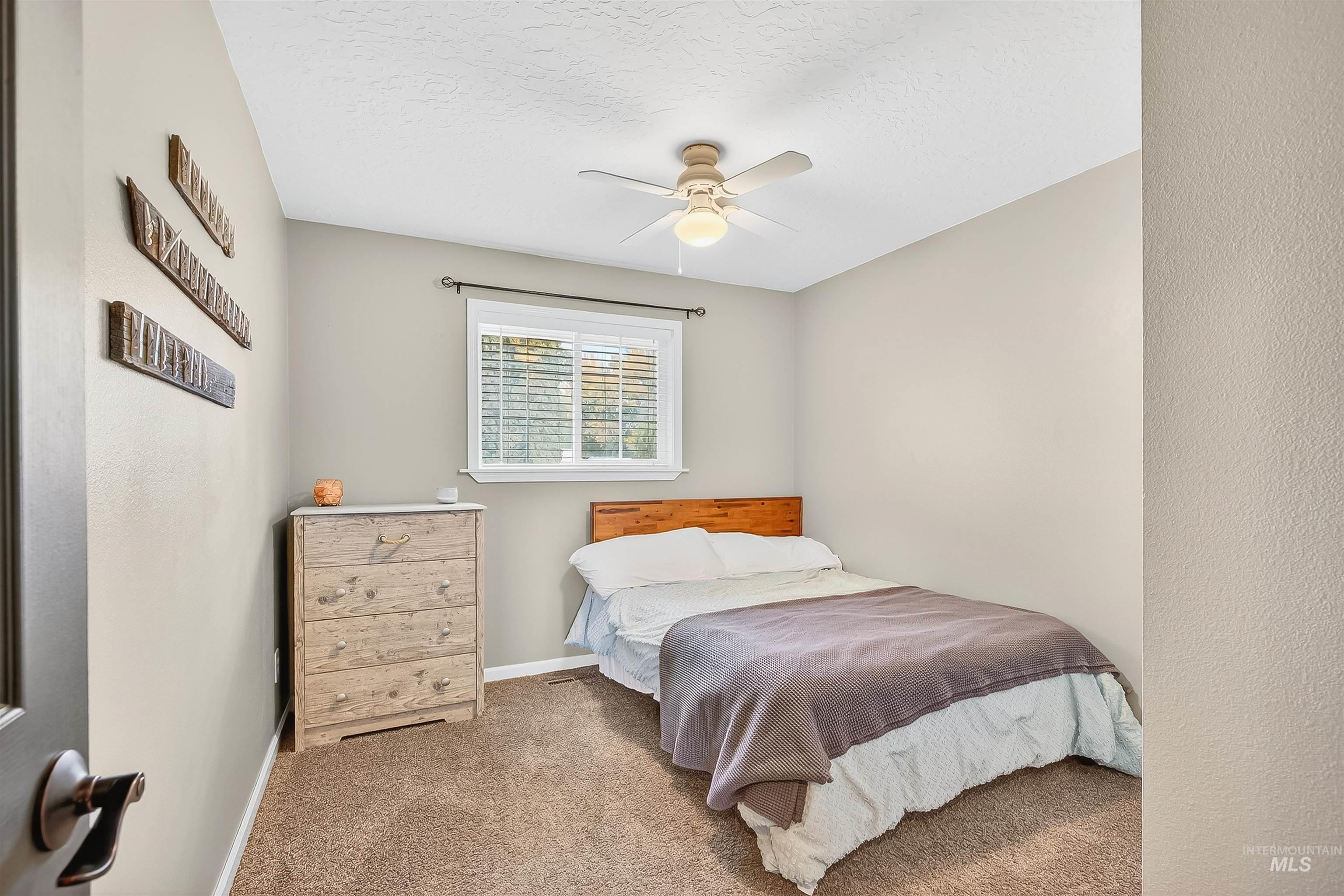 Bedroom with carpet flooring, a textured ceiling, and ceiling fan