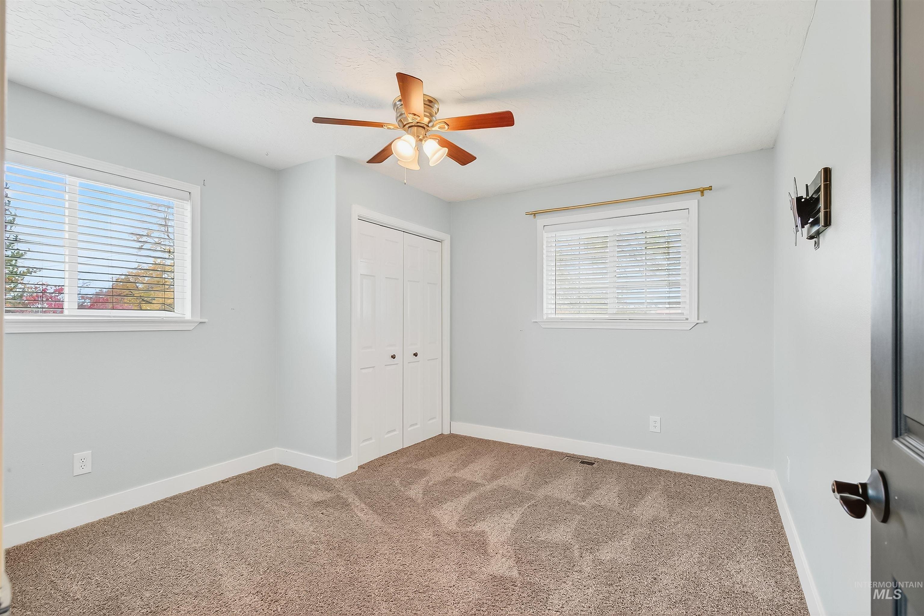 Unfurnished bedroom featuring carpet flooring, ceiling fan, a closet, and a textured ceiling