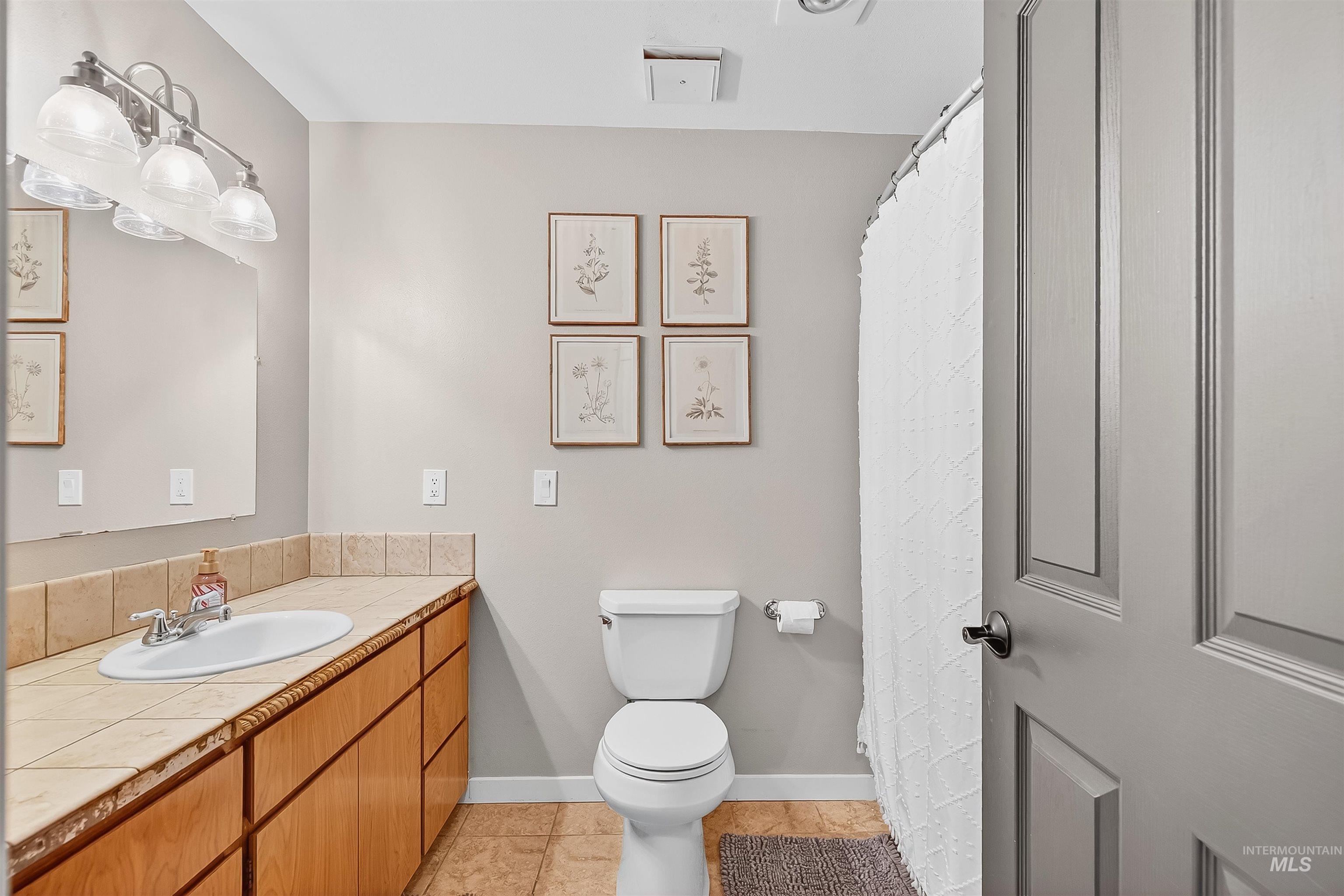 Full bath featuring light tile patterned floors, vanity, and a shower with shower curtain