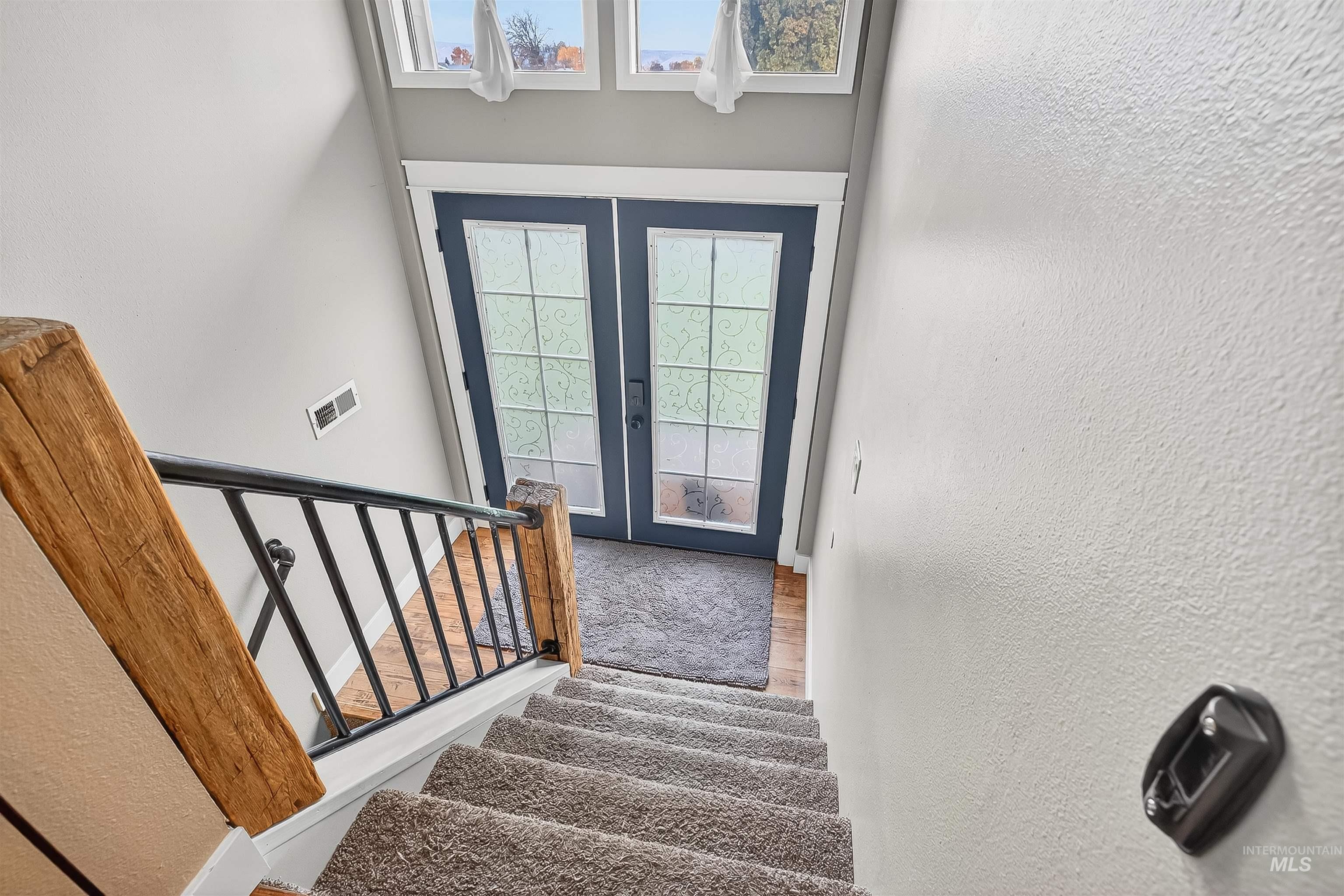 Stairway with a textured wall, french doors, healthy amount of natural light, and wood finished floors