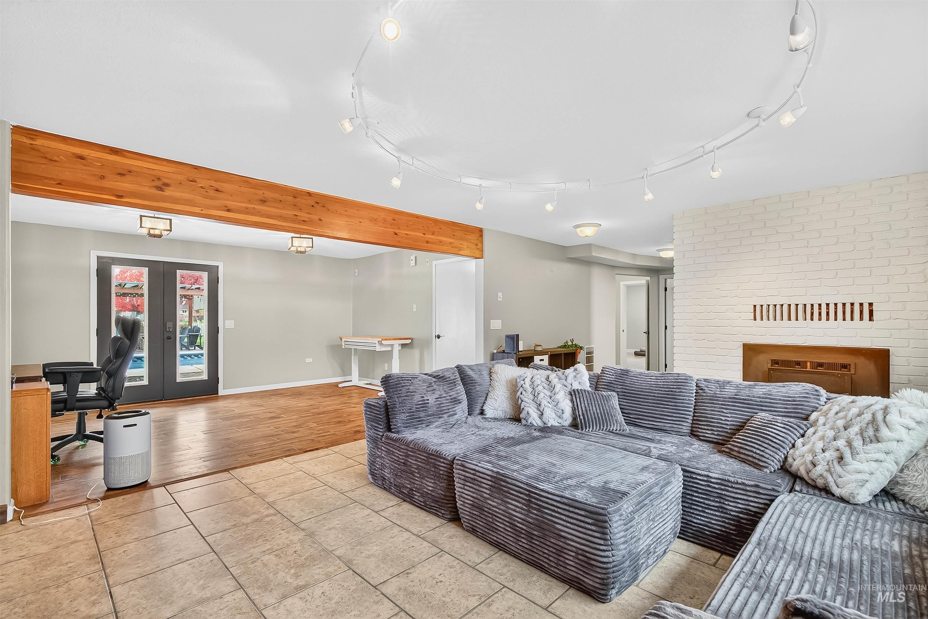 Living area with a desk, light tile patterned floors, and french doors