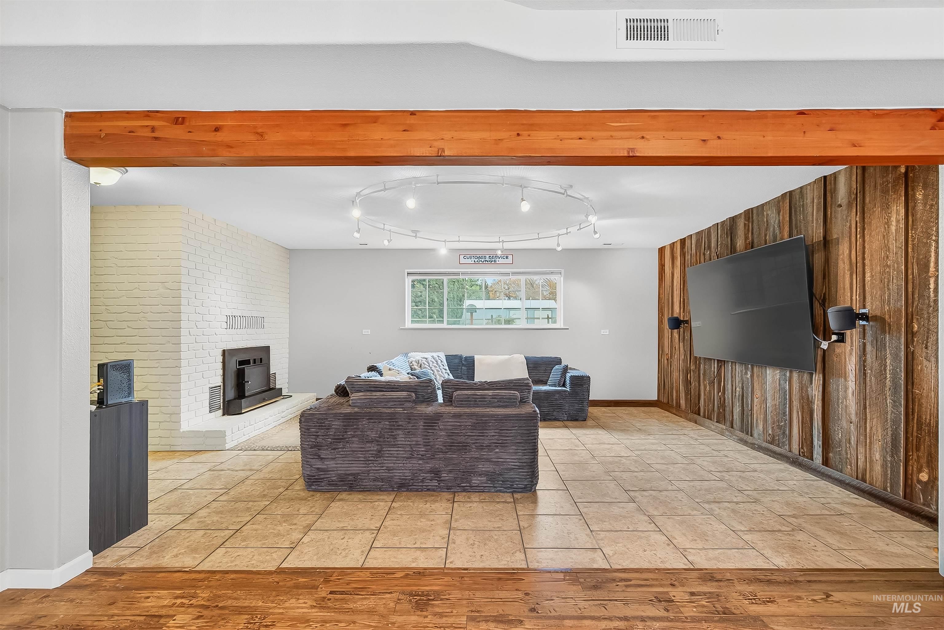Living area featuring wood walls, light wood-style flooring, beamed ceiling, and a fireplace