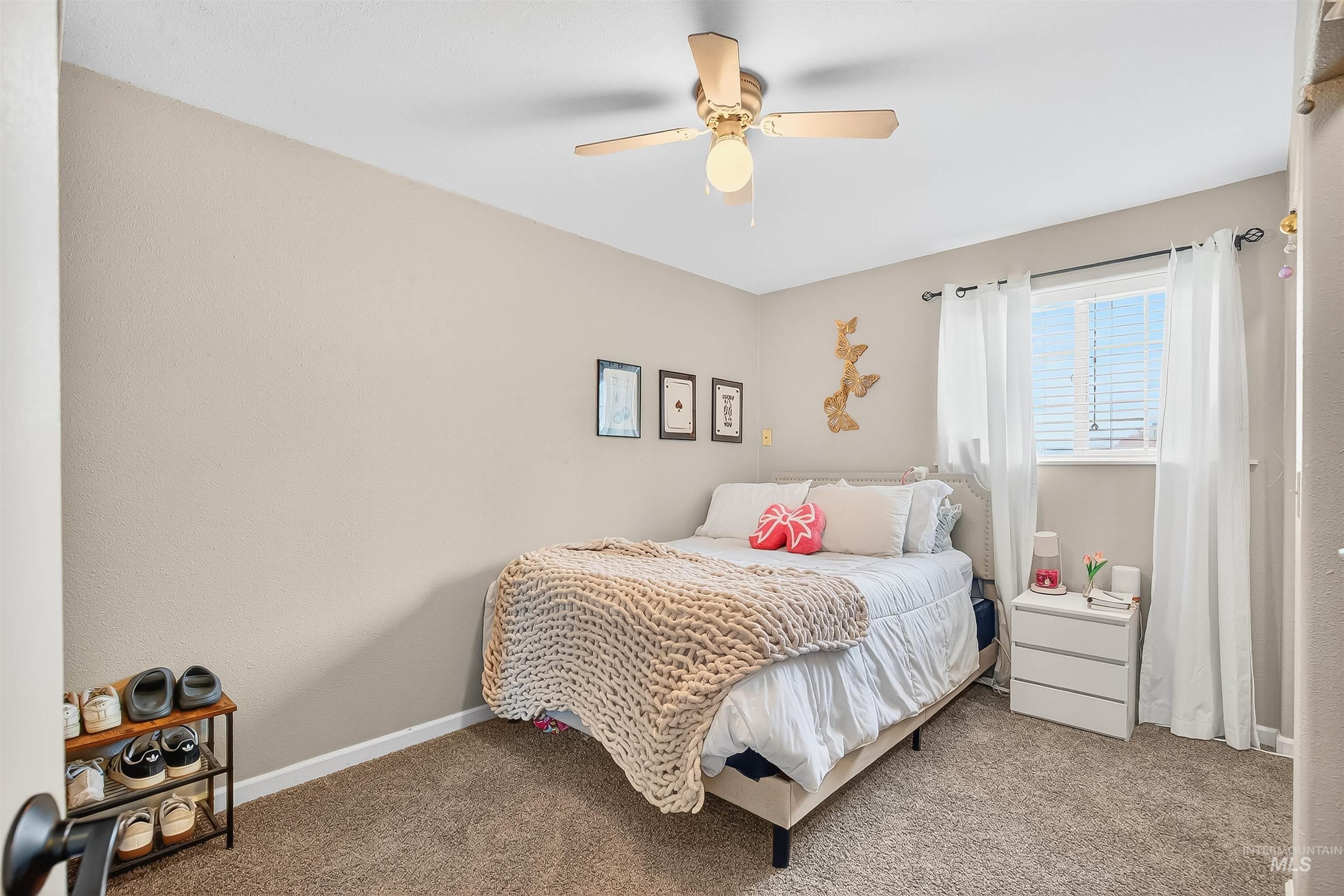 Carpeted bedroom with ceiling fan and baseboards