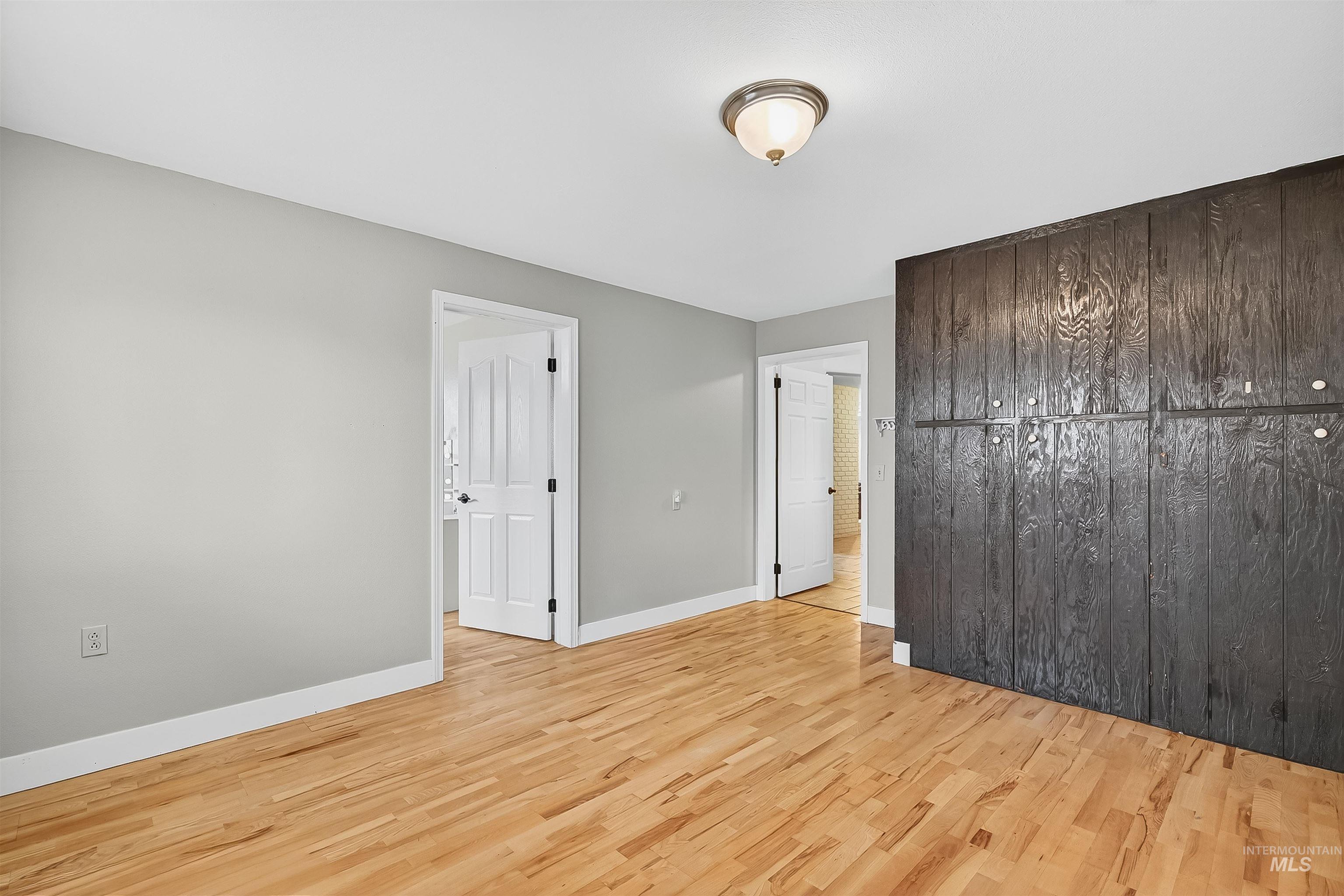 Unfurnished bedroom with light wood finished floors and baseboards