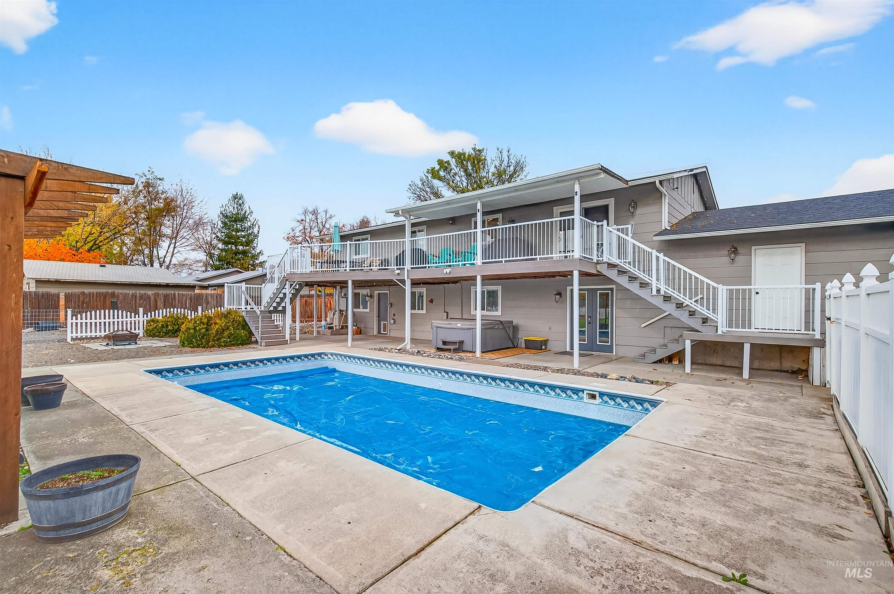 View of pool featuring stairs, a hot tub, a patio, a deck, and a fenced backyard