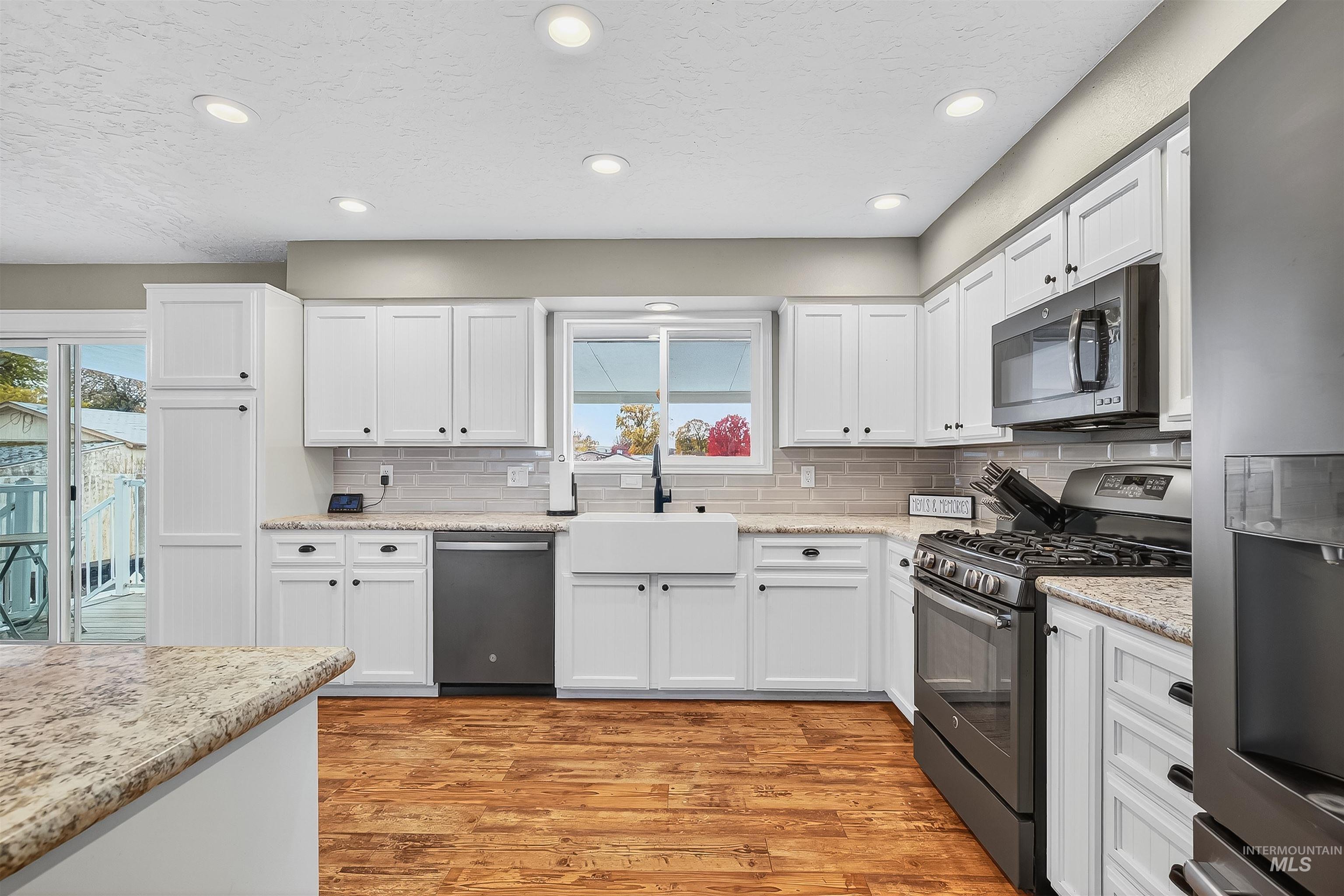 Kitchen featuring stainless steel appliances, white cabinetry, a textured ceiling, recessed lighting, and light wood-style floors