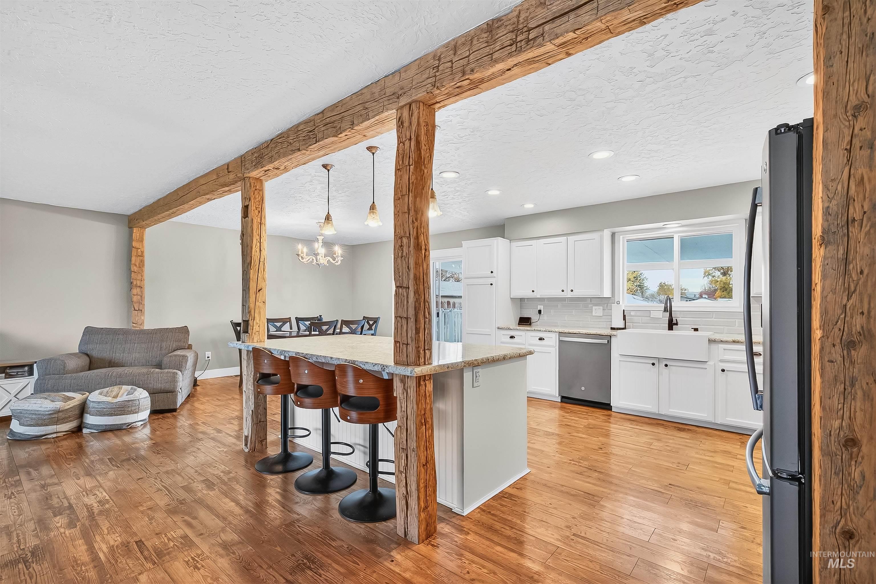 Kitchen with a kitchen breakfast bar, open floor plan, white cabinets, appliances with stainless steel finishes, and light wood-style floors