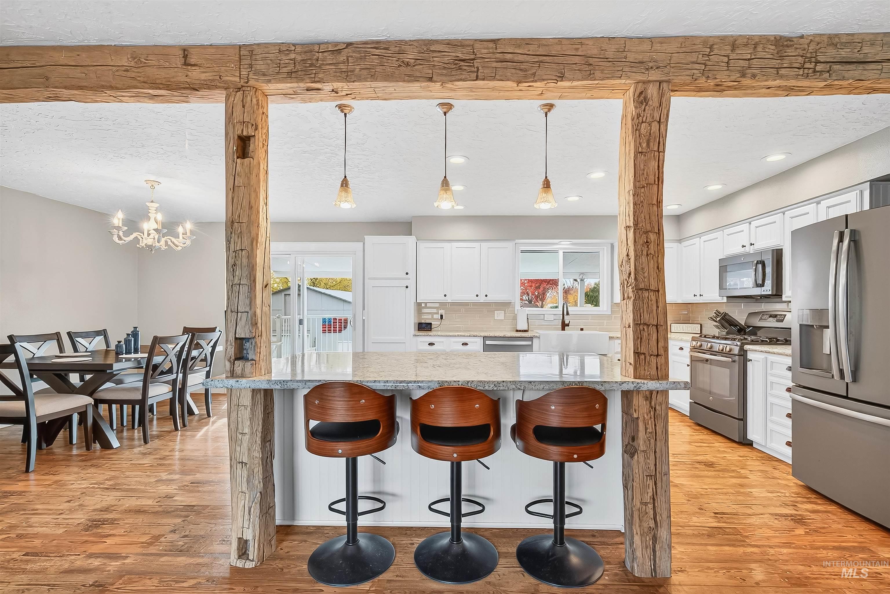 Kitchen featuring a breakfast bar area, light stone countertops, white cabinetry, pendant lighting, and a textured ceiling