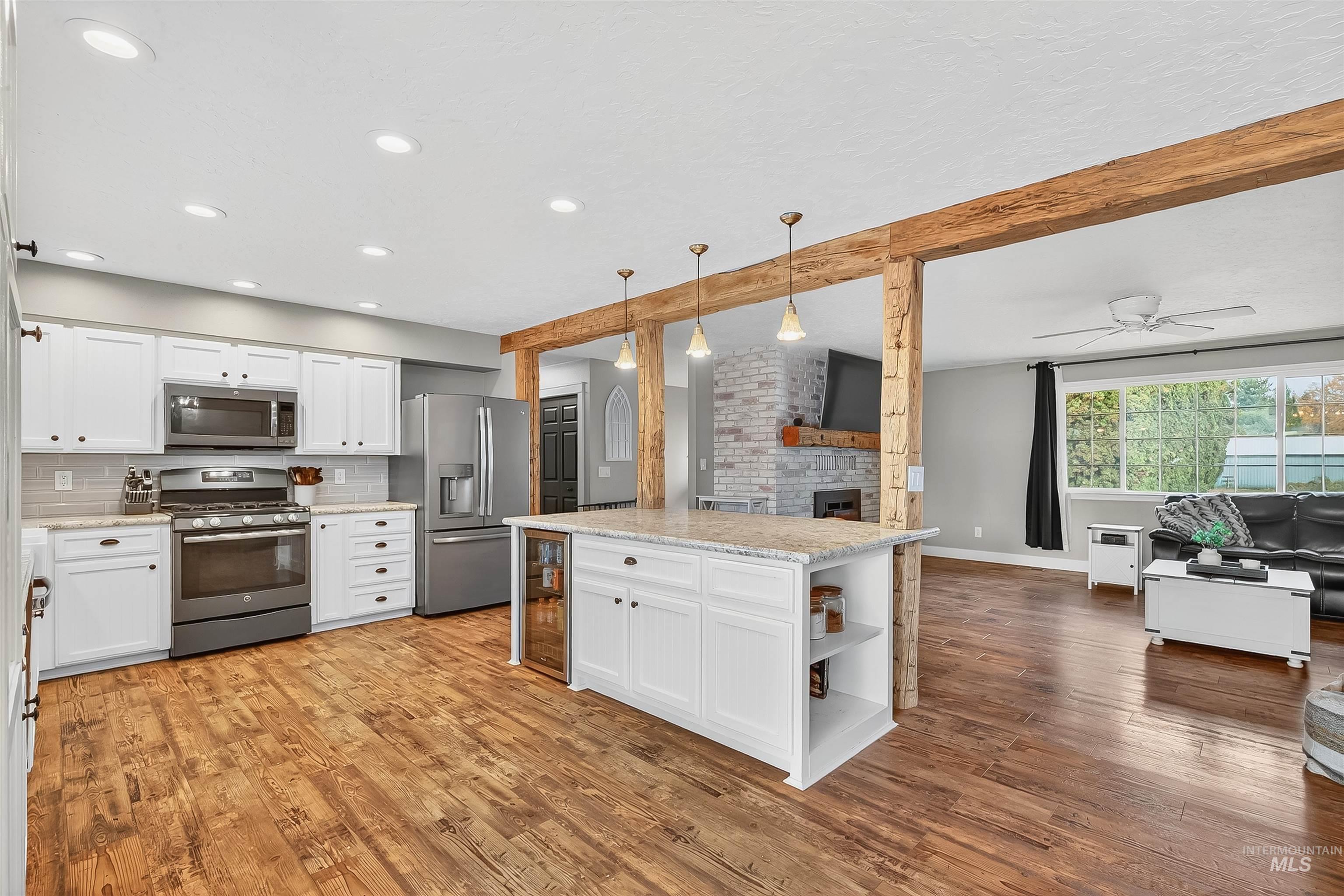 Kitchen with white cabinets, open floor plan, hanging light fixtures, and beamed ceiling