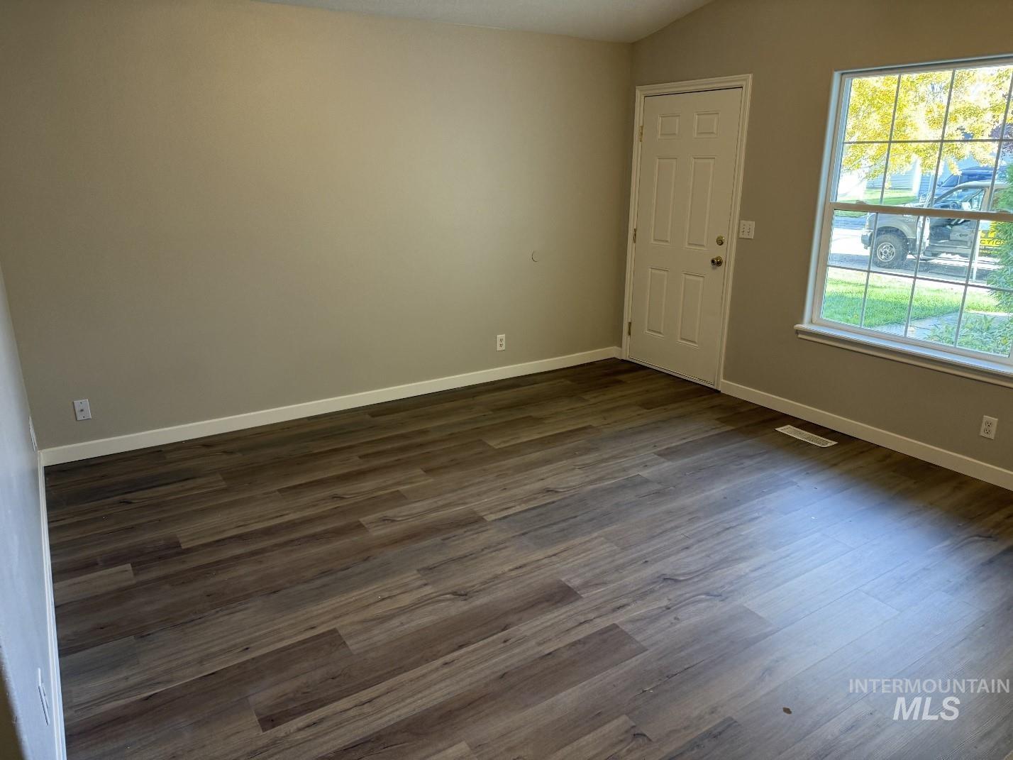 Unfurnished room with dark wood-type flooring and vaulted ceiling