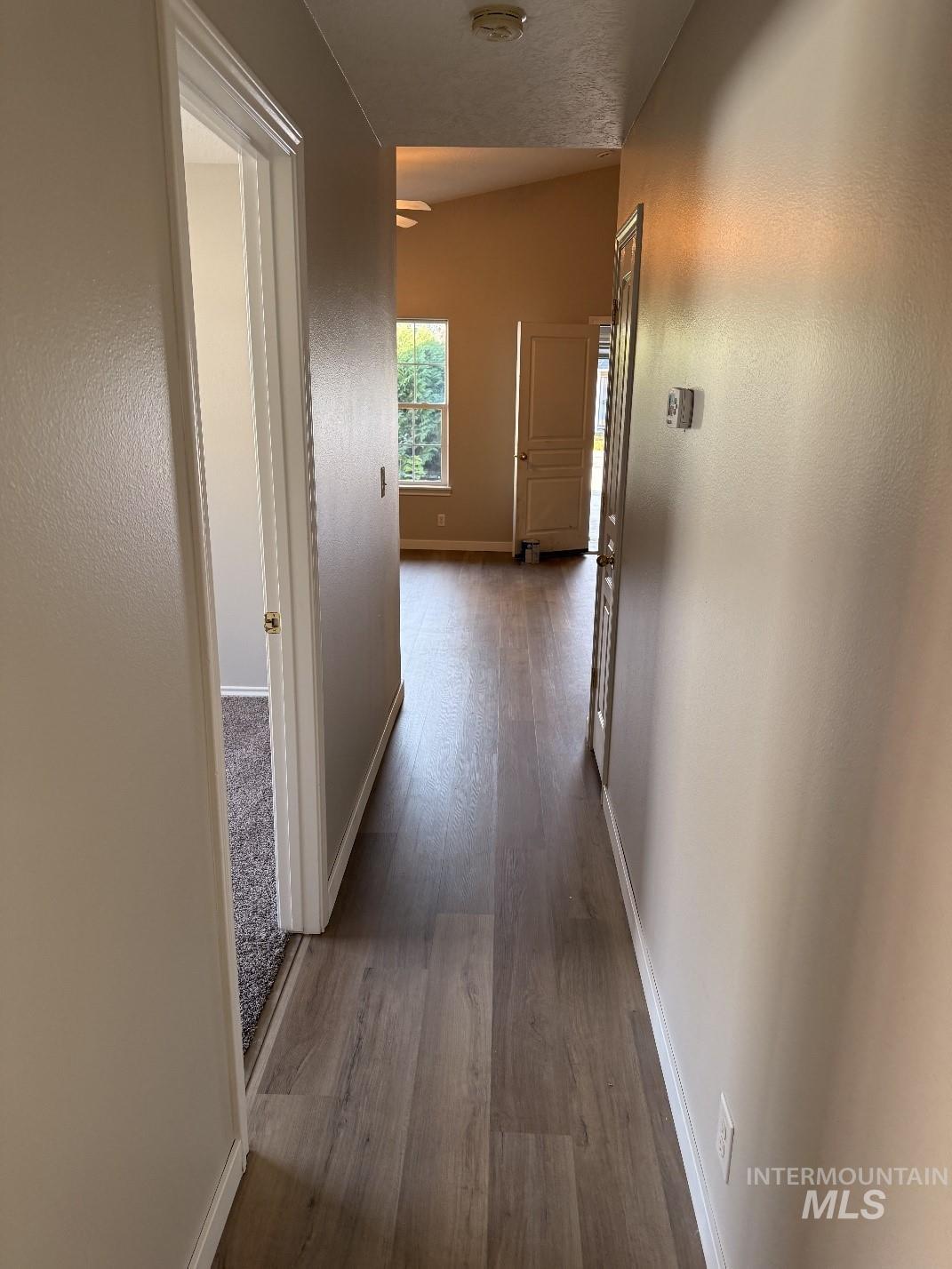 Hallway with dark wood finished floors and a textured wall
