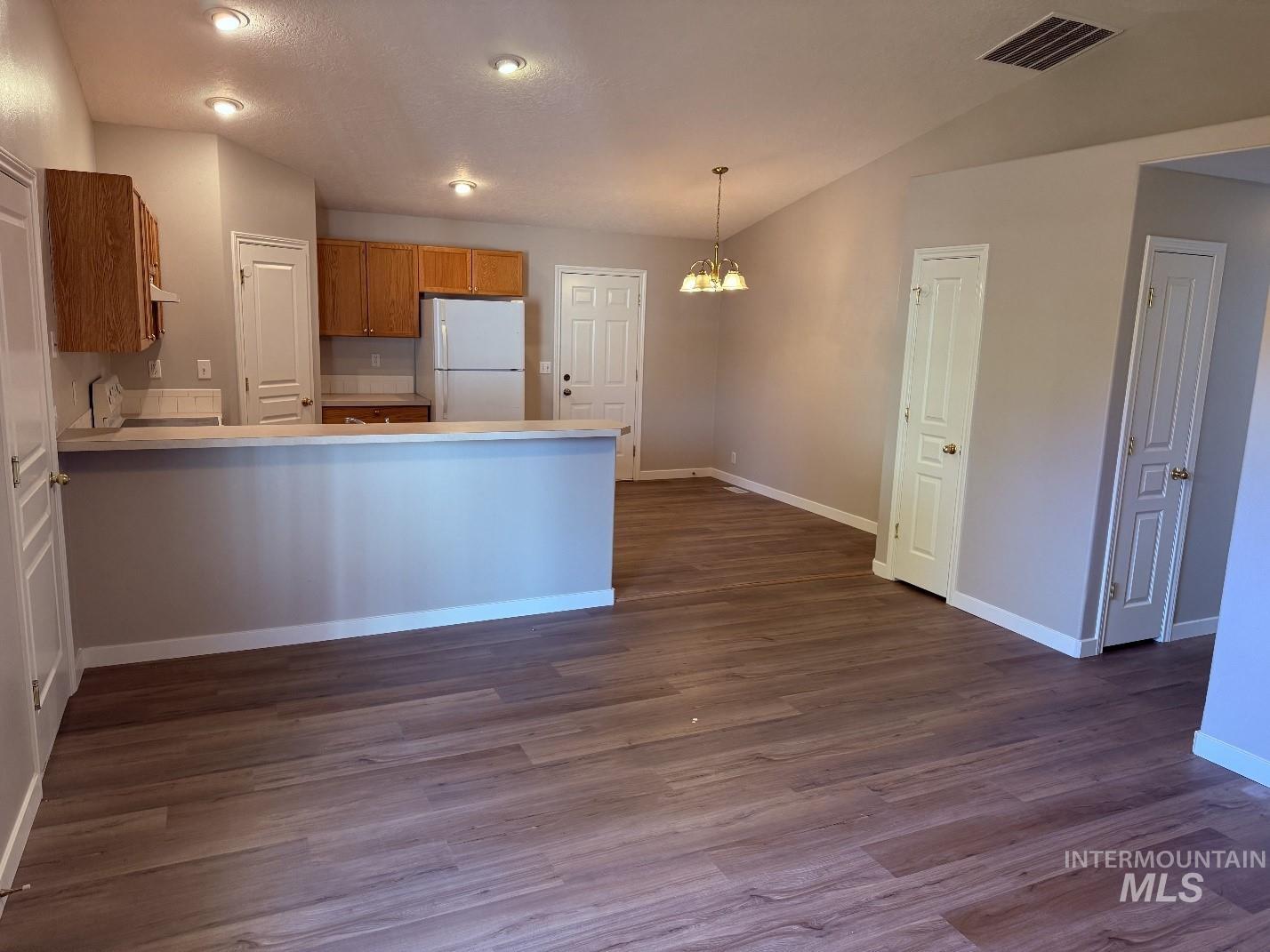 Kitchen with a chandelier, light countertops, a peninsula, freestanding refrigerator, and decorative light fixtures