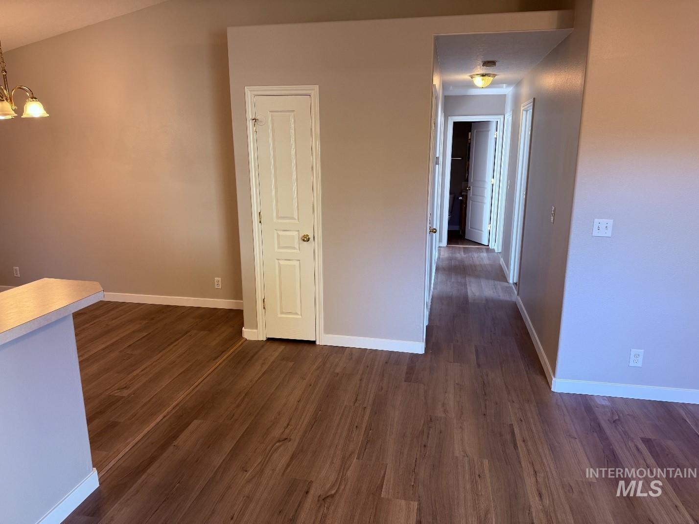 Unfurnished room with dark wood-style floors and a chandelier