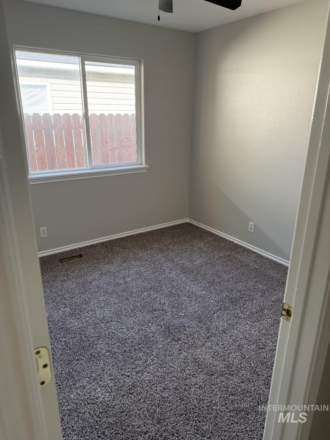 Carpeted spare room featuring baseboards and ceiling fan