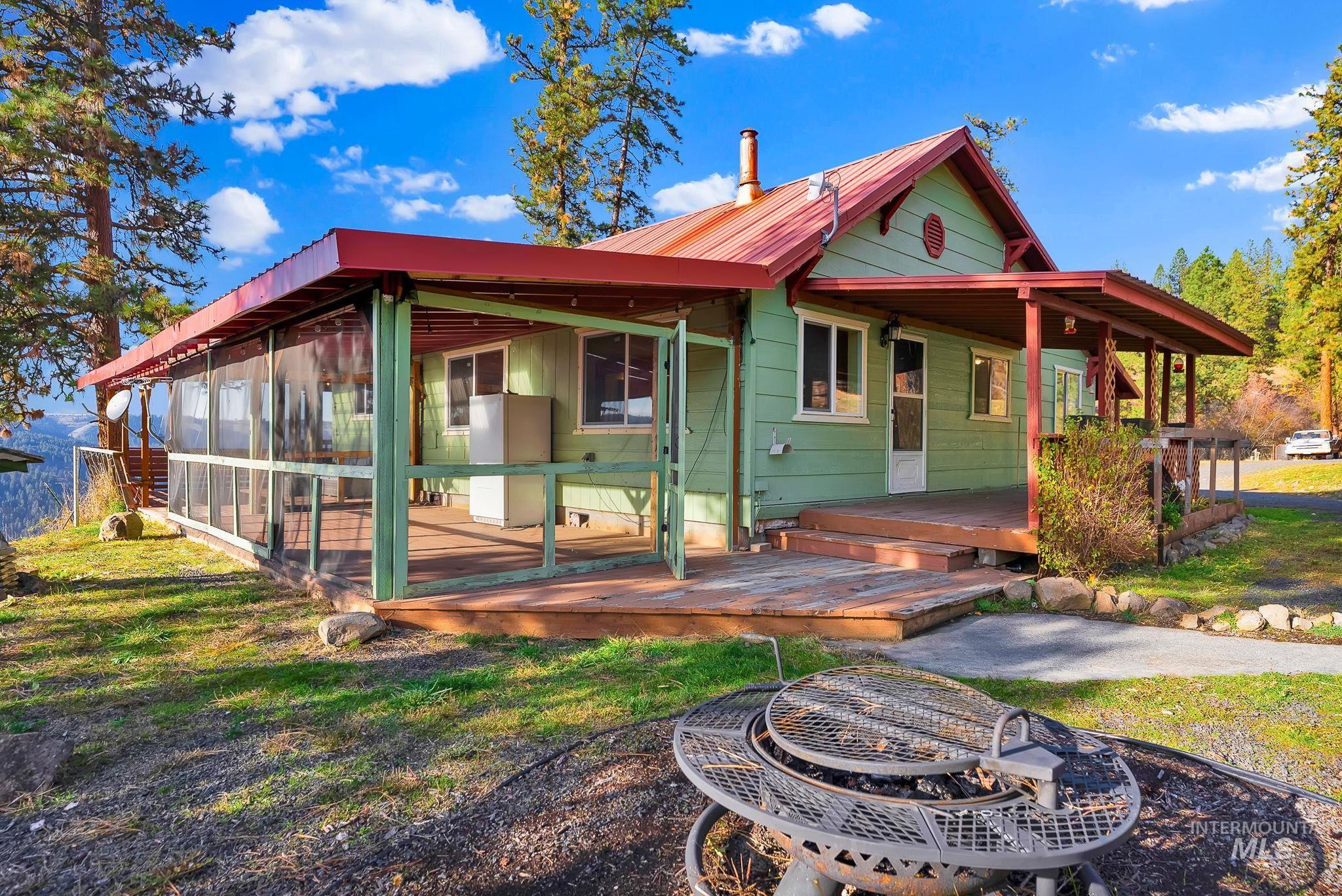 Rear view of property with an outdoor fire pit, a metal roof, a yard, and a deck