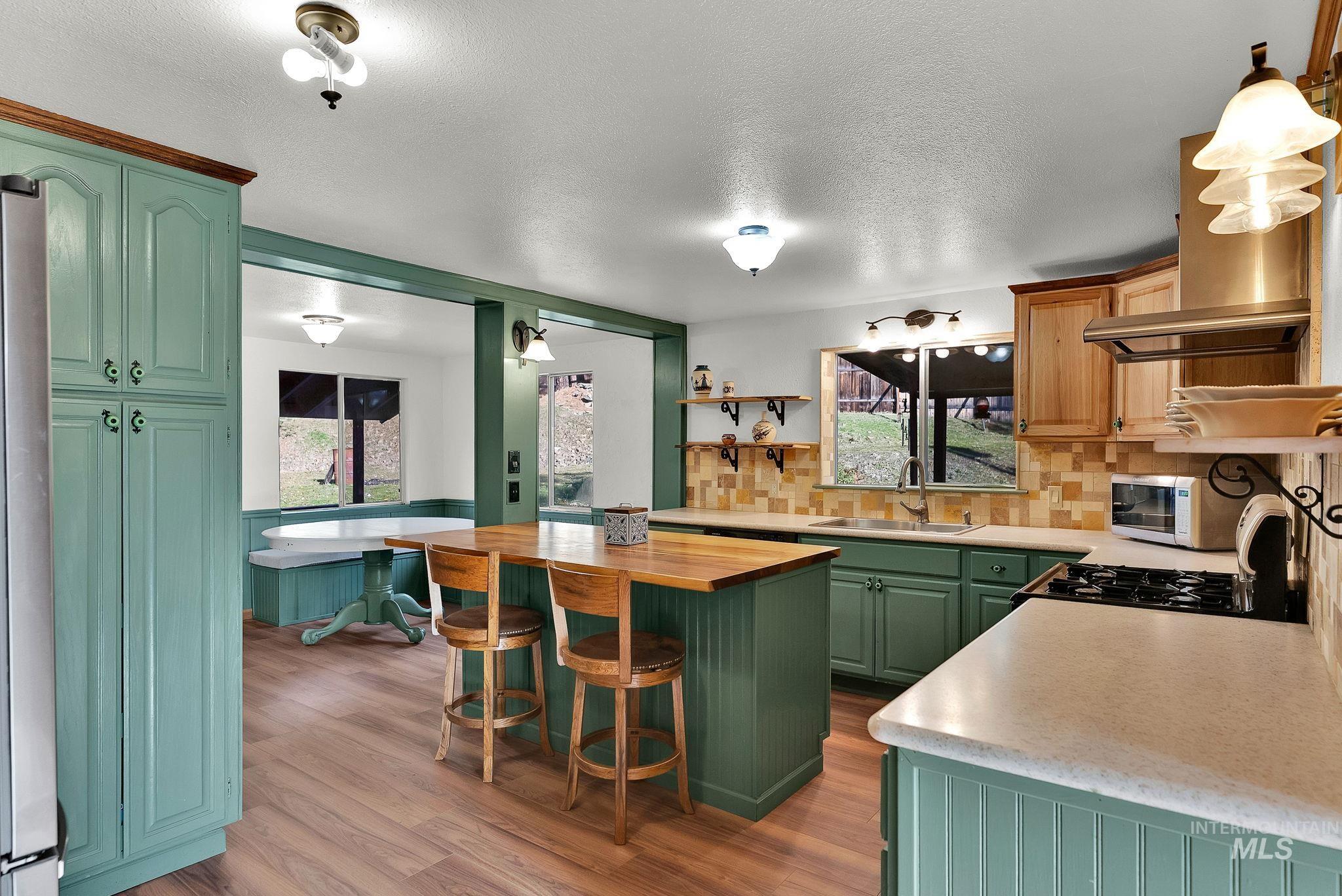 Kitchen featuring wooden counters, green cabinets, a kitchen bar, backsplash, and light wood-style flooring