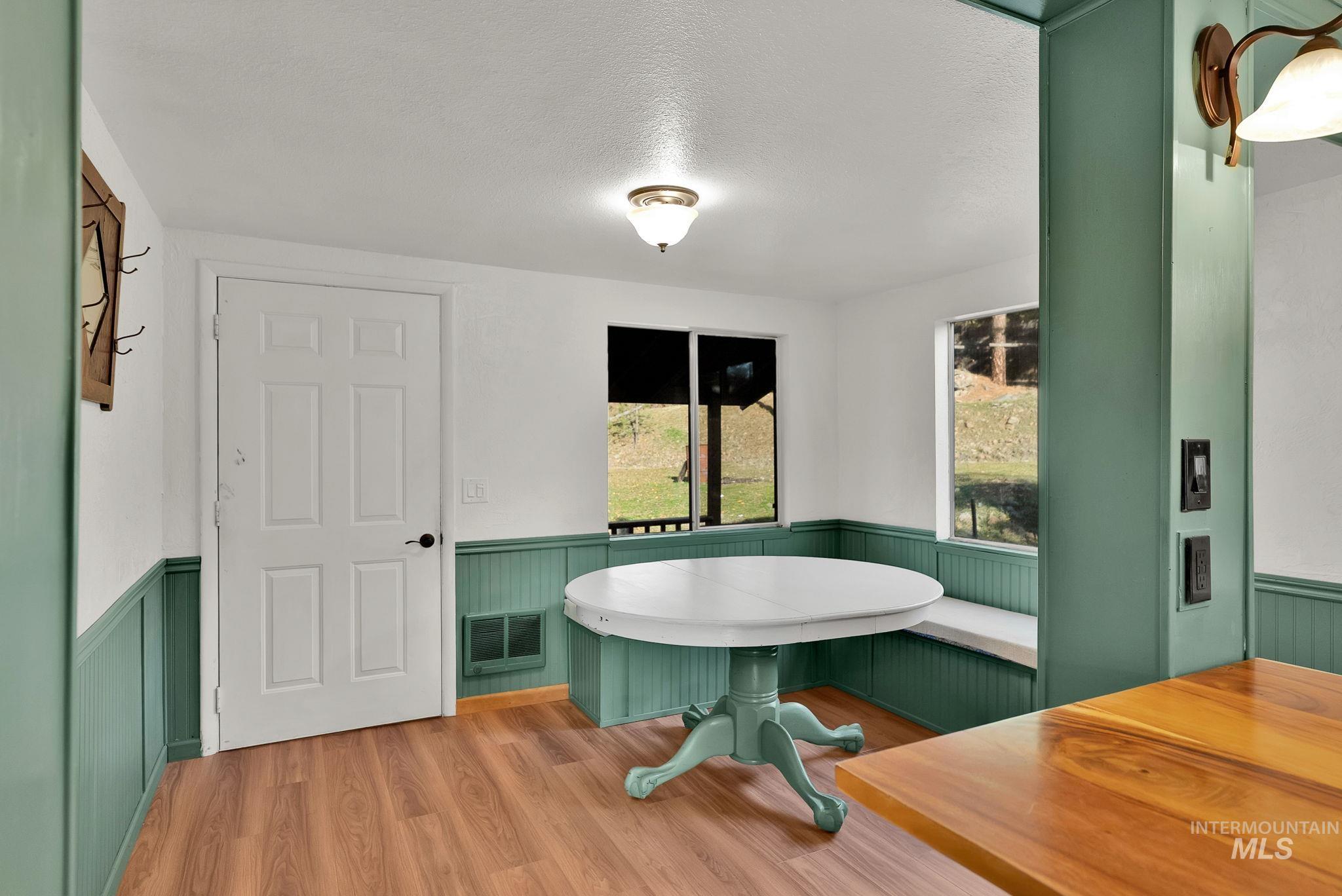 Dining space with wainscoting, wood finished floors, and a textured ceiling