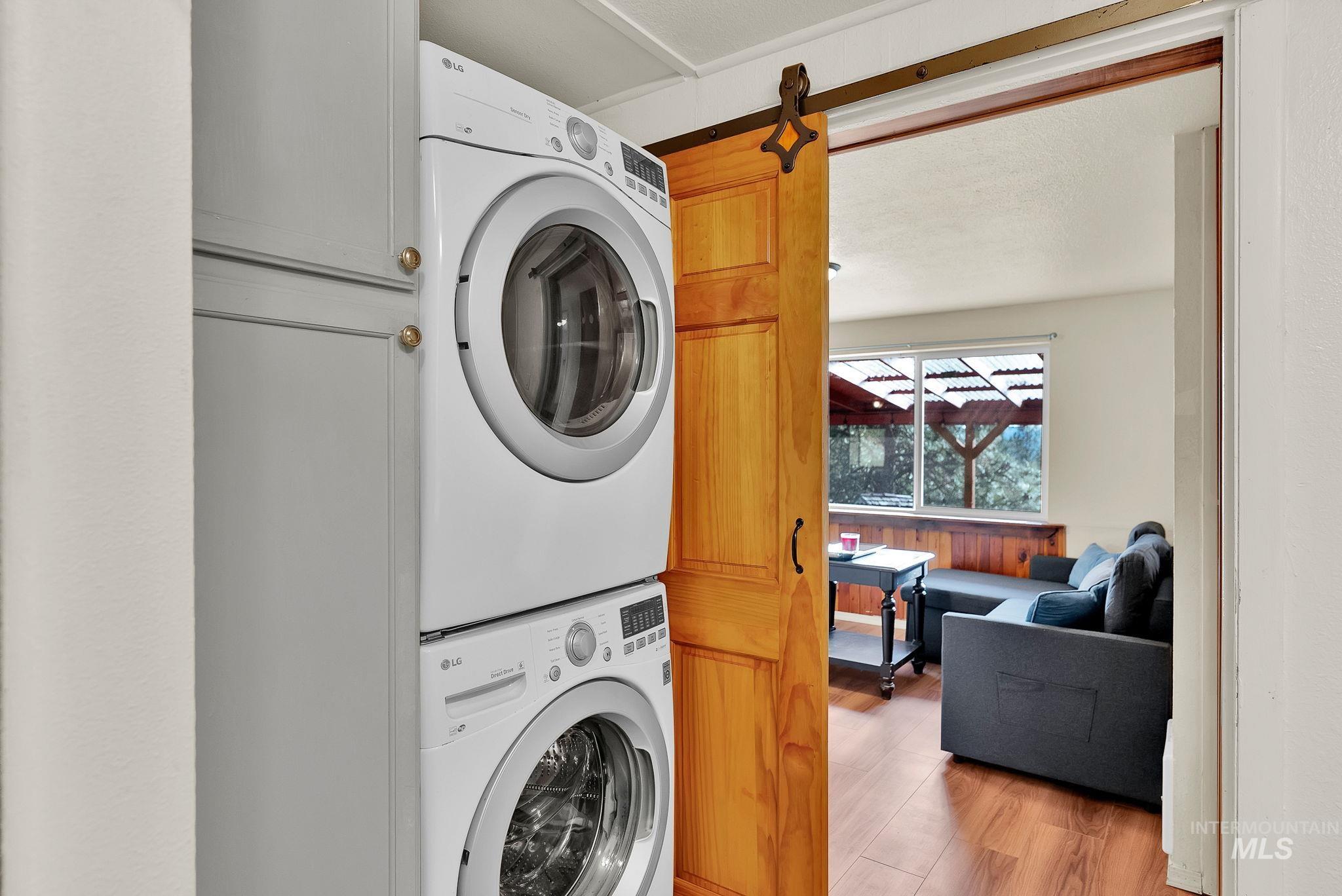 Laundry area featuring light wood finished floors and estacked washer and dryer
