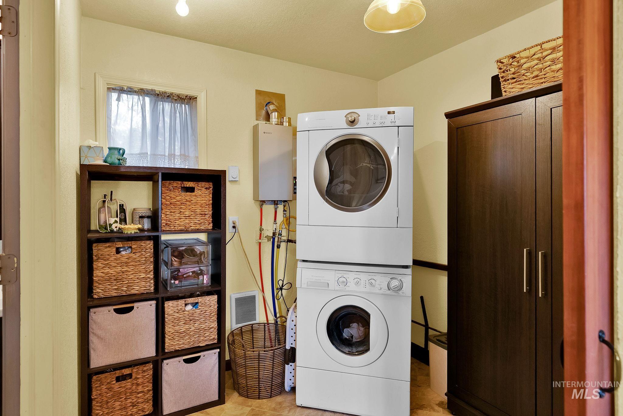 Laundry area with stacked washer / dryer and tankless water heater