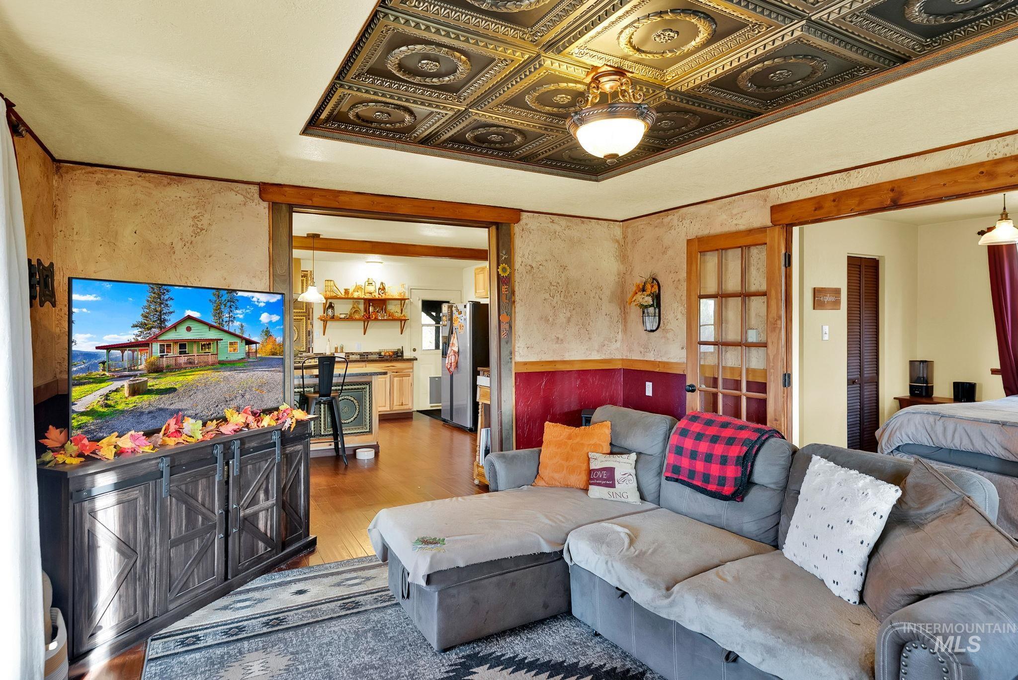 Living room with wood finished floors, an ornate ceiling, and a wainscoted wall