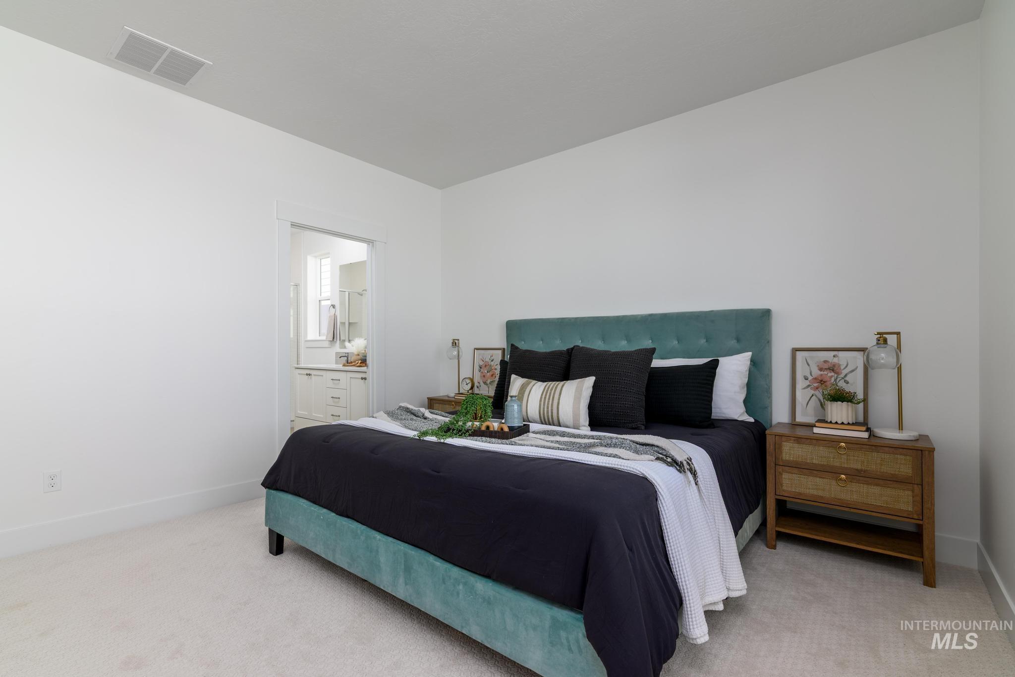 Bedroom with light colored carpet and ensuite bathroom