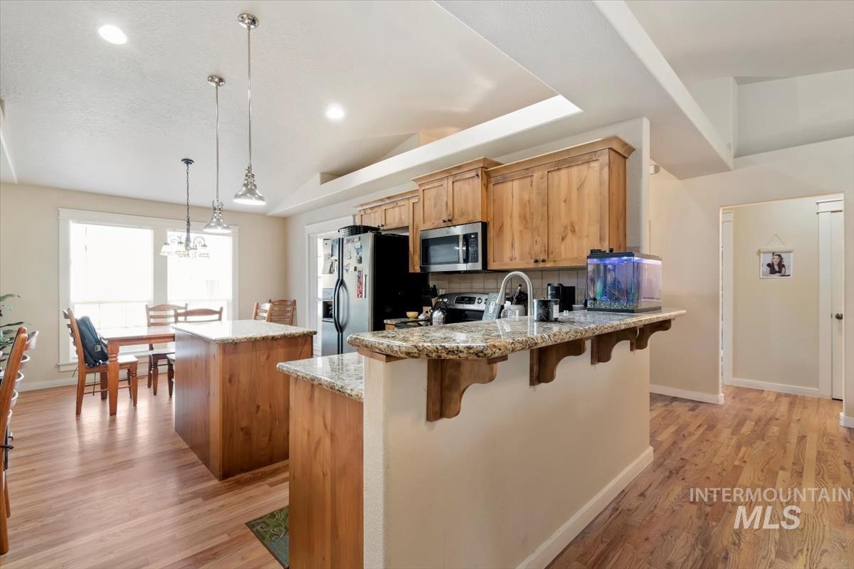 Kitchen featuring a center island, decorative light fixtures, light stone counters, decorative backsplash, and recessed lighting