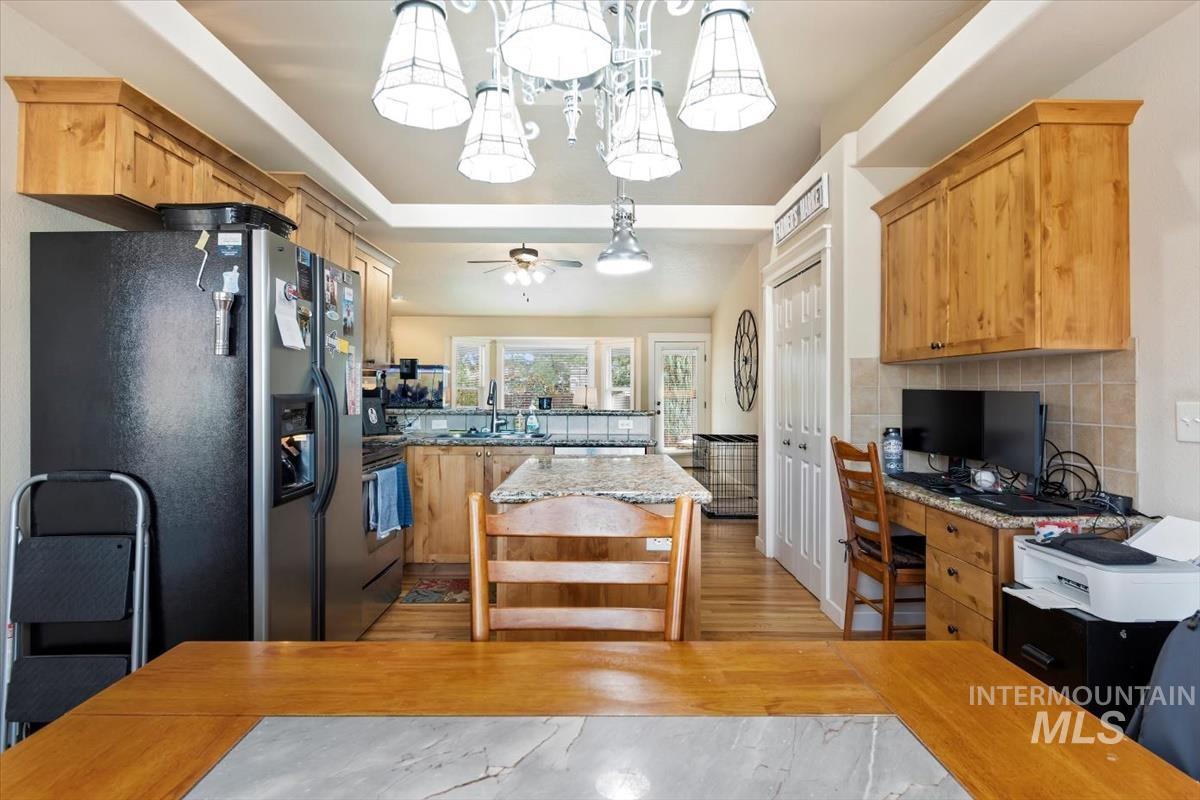 Kitchen with stainless steel fridge with ice dispenser, light wood-type flooring, a kitchen island, light stone countertops, and an office area