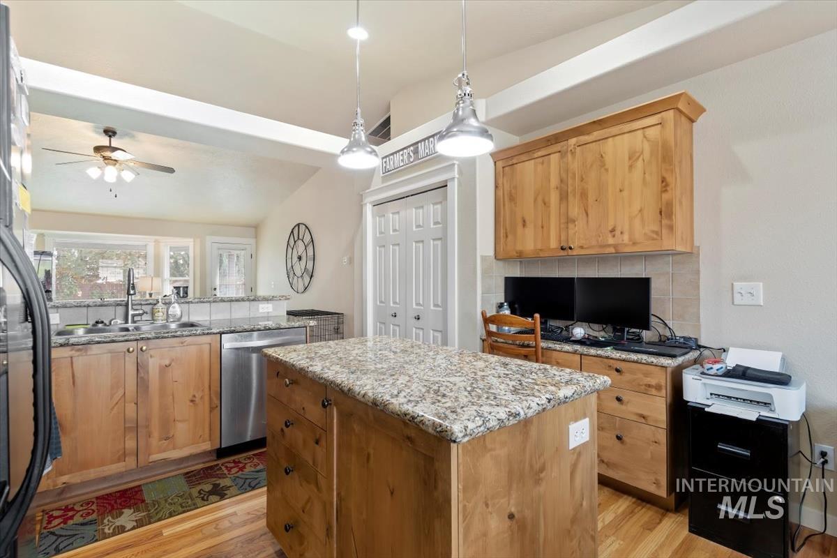 Kitchen featuring light stone counters, a peninsula, decorative backsplash, a kitchen island, and lofted ceiling
