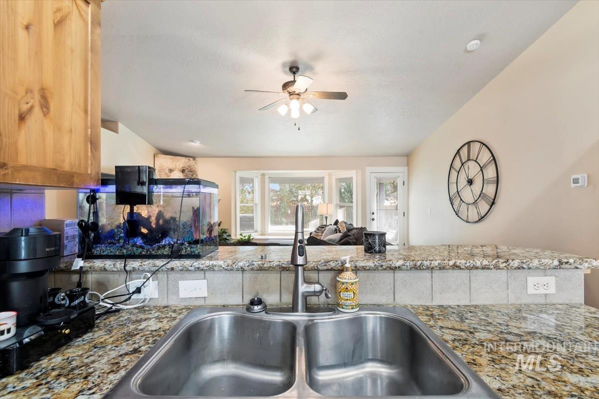Kitchen with dark stone counters, ceiling fan, and open floor plan