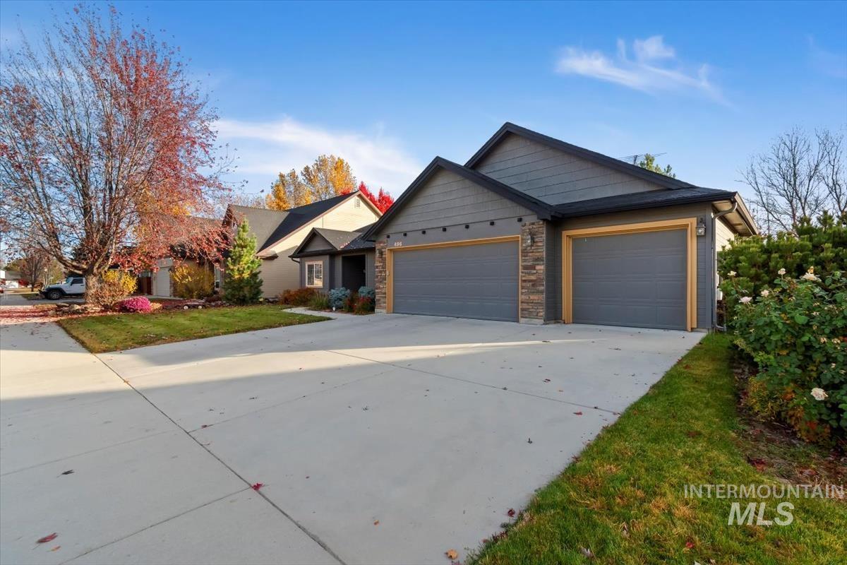 Craftsman-style home featuring an attached garage, concrete driveway, and stone siding