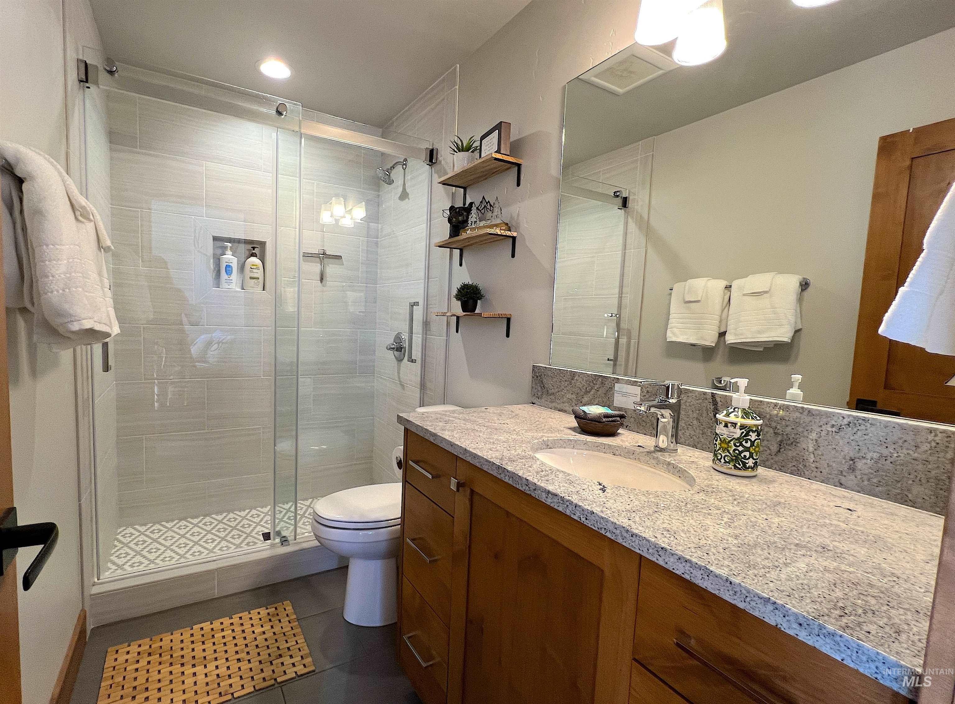 Bathroom with vanity, a shower stall, dark tile patterned flooring, and recessed lighting