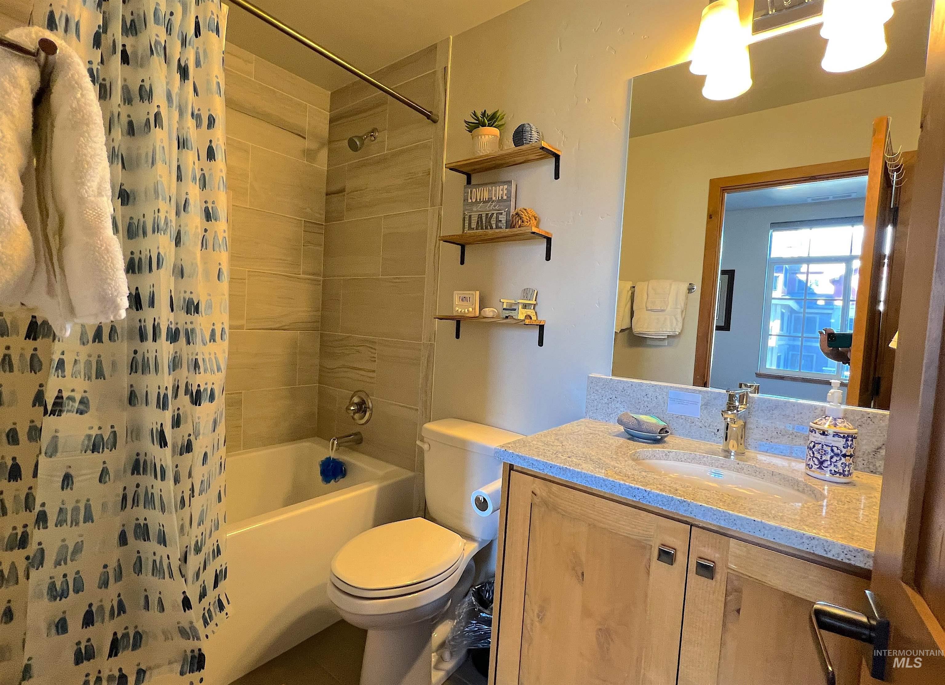 Bathroom featuring shower / bath combo with shower curtain, vanity, and tile patterned flooring
