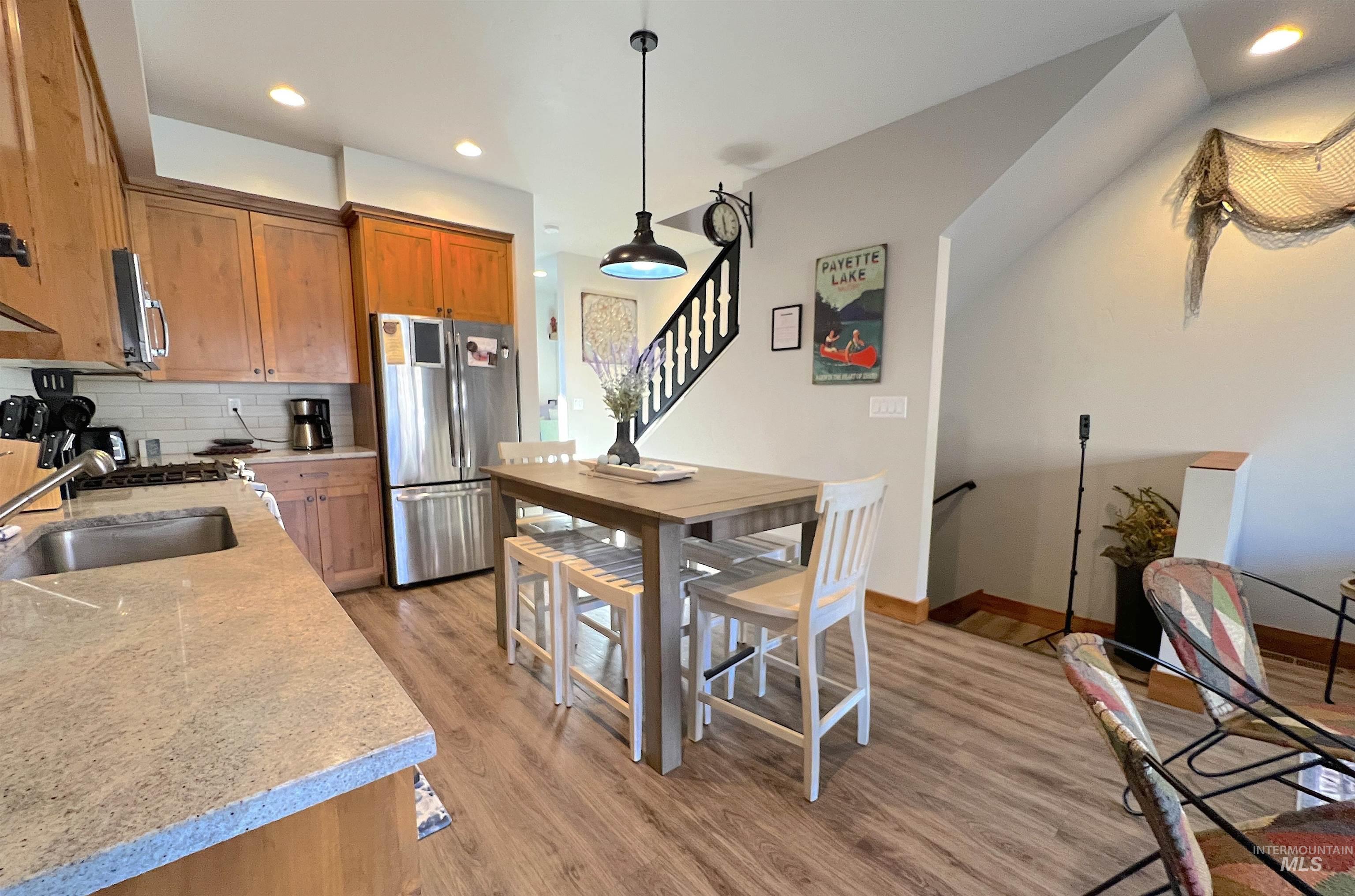 Kitchen with backsplash, brown cabinets, light wood finished floors, appliances with stainless steel finishes, and recessed lighting