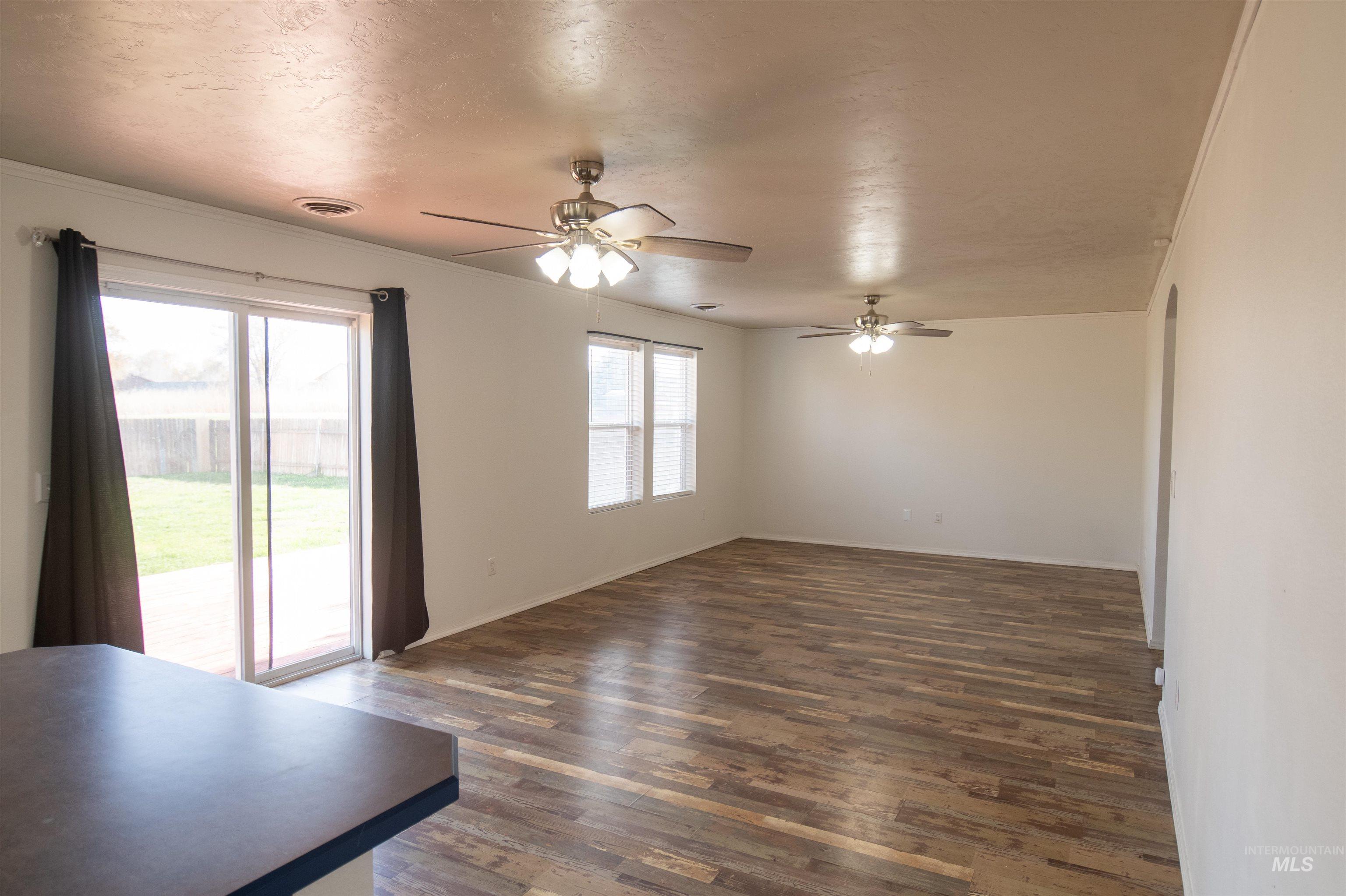 Unfurnished living room with dark wood-type flooring, a ceiling fan, and a textured ceiling