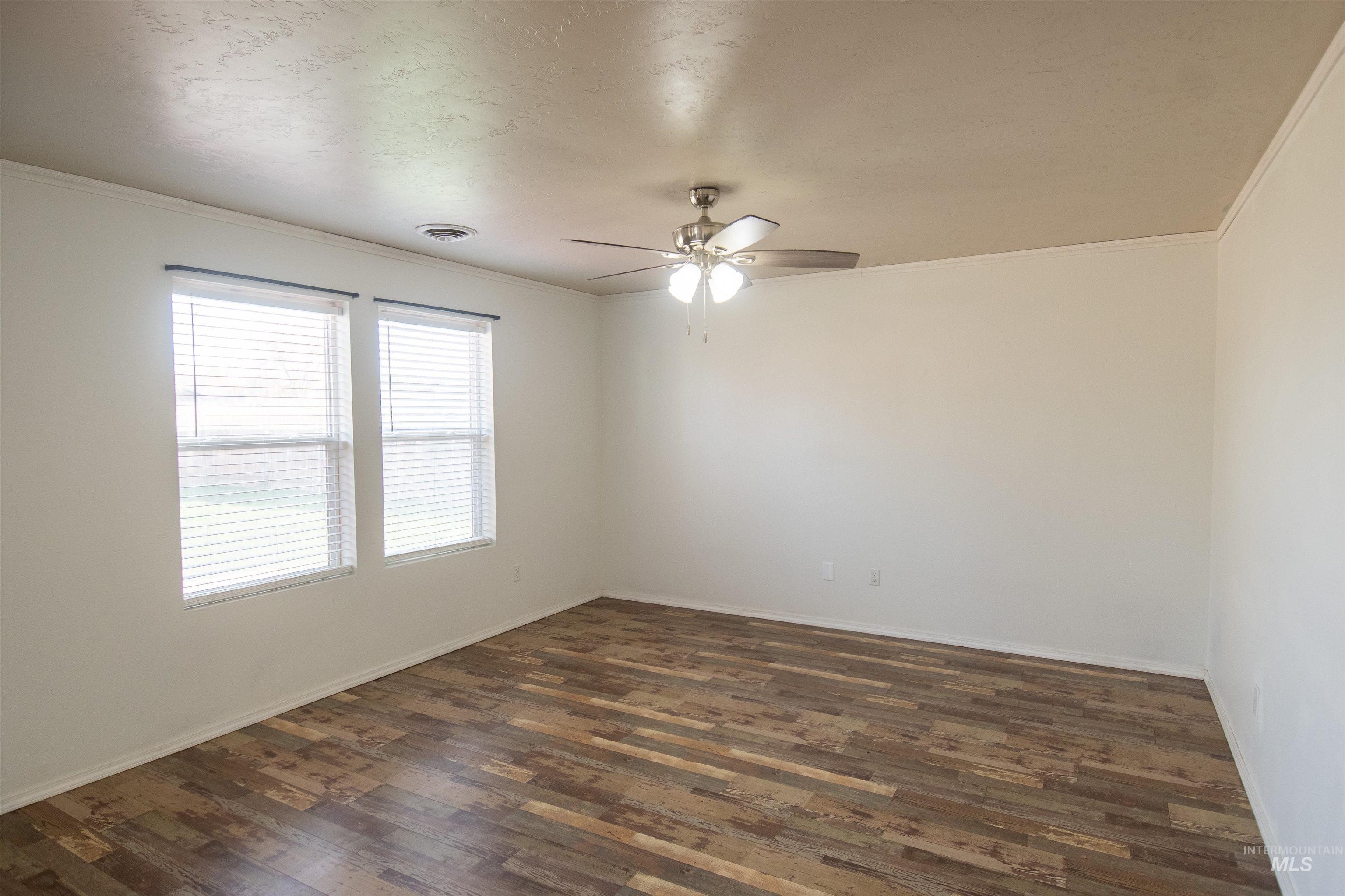 Unfurnished room with crown molding, dark wood-style floors, ceiling fan, and a textured ceiling