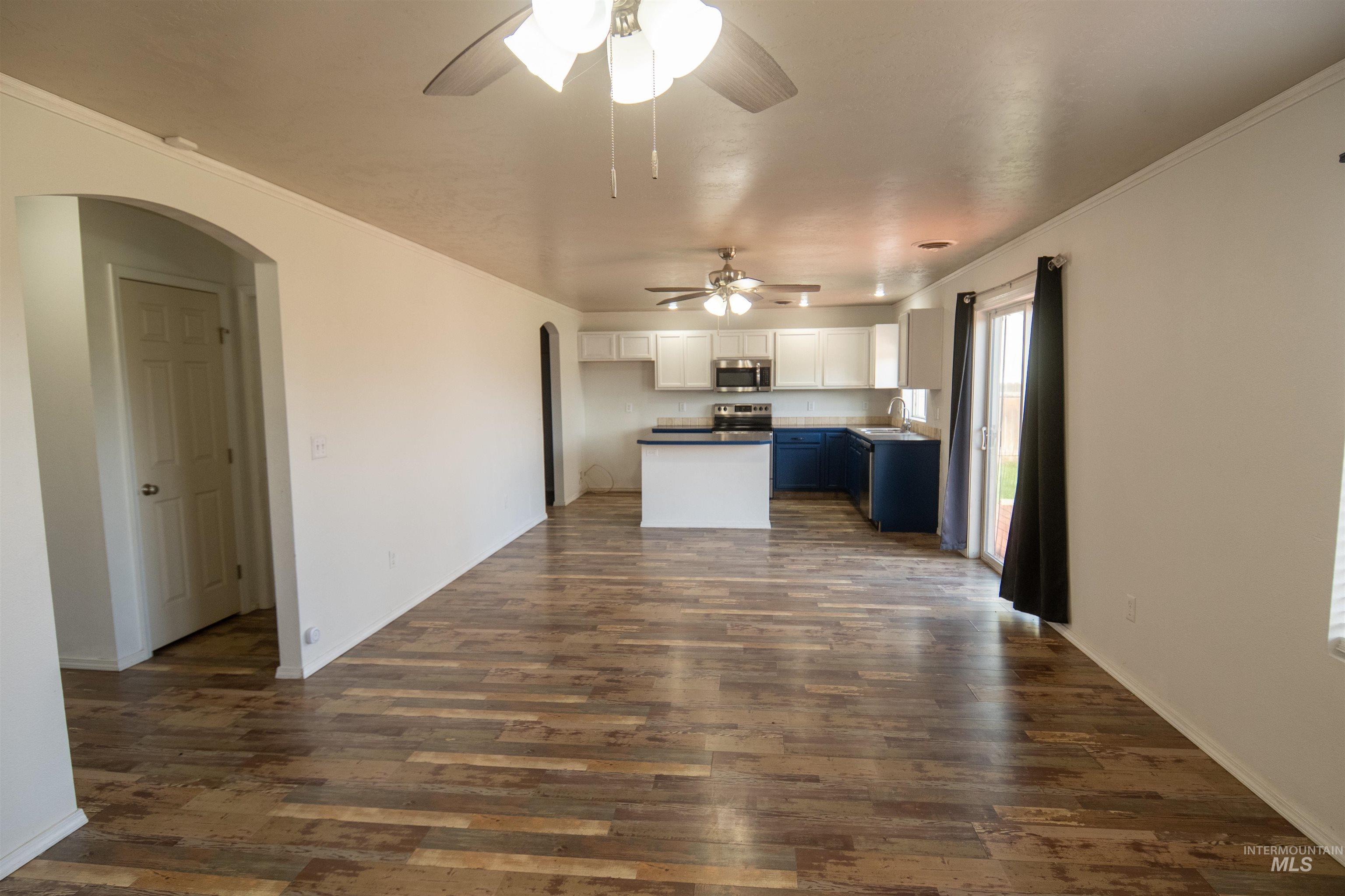 Kitchen with arched walkways, crown molding, white cabinetry, blue cabinets, and open floor plan