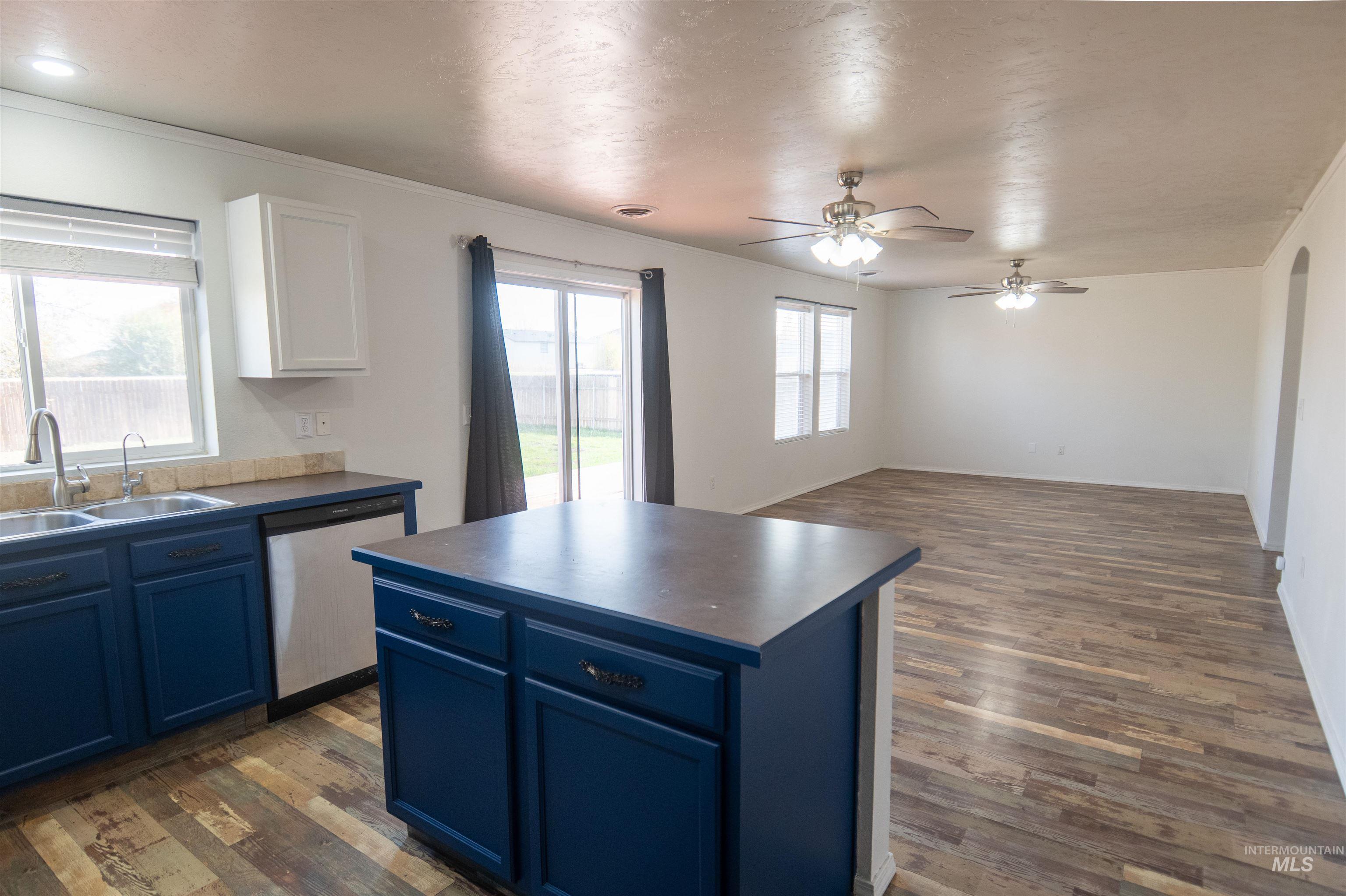 Kitchen with blue cabinetry, dark wood-style flooring, open floor plan, and a textured ceiling