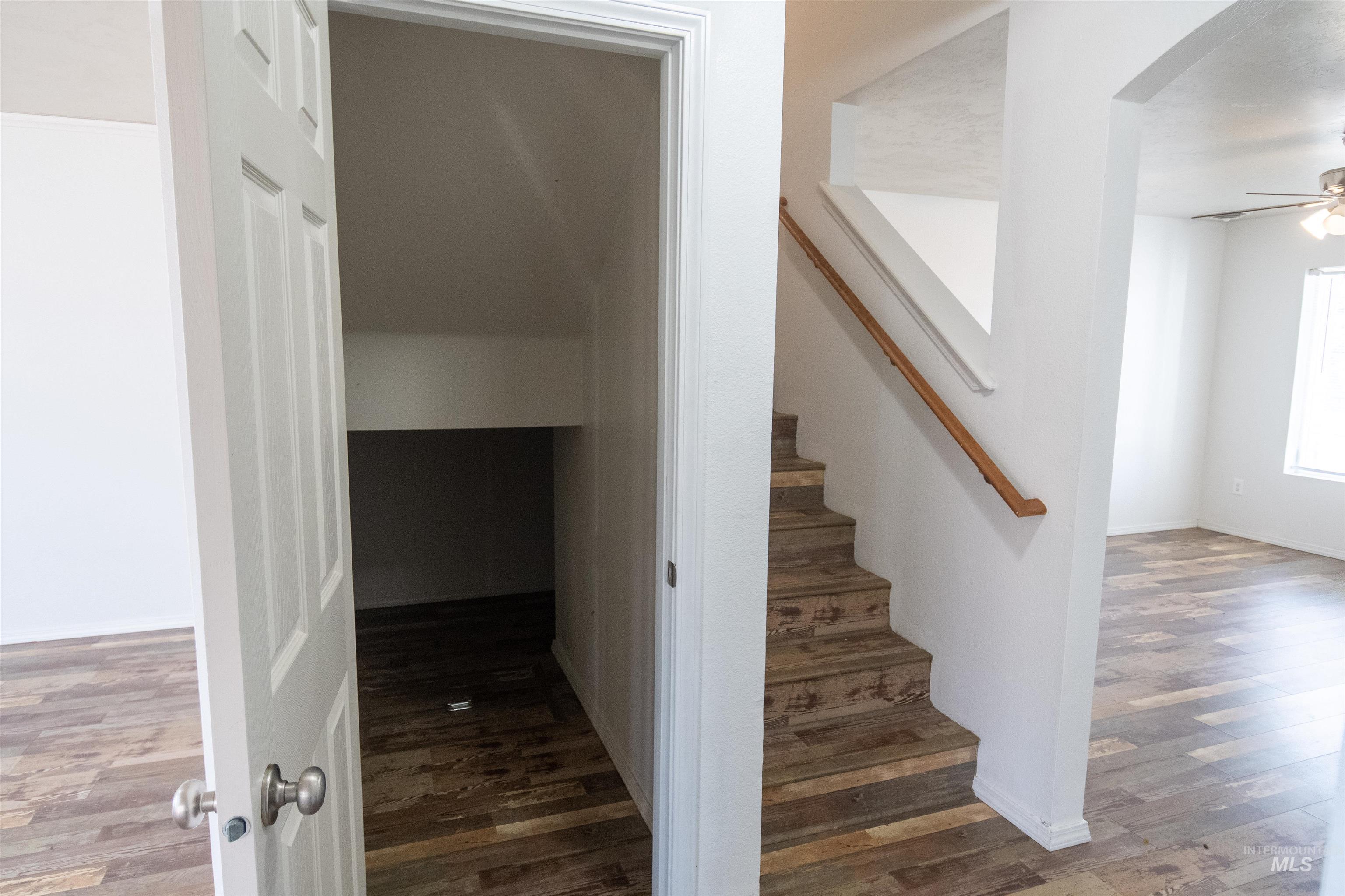 Stairs with wood finished floors, arched walkways, and a ceiling fan