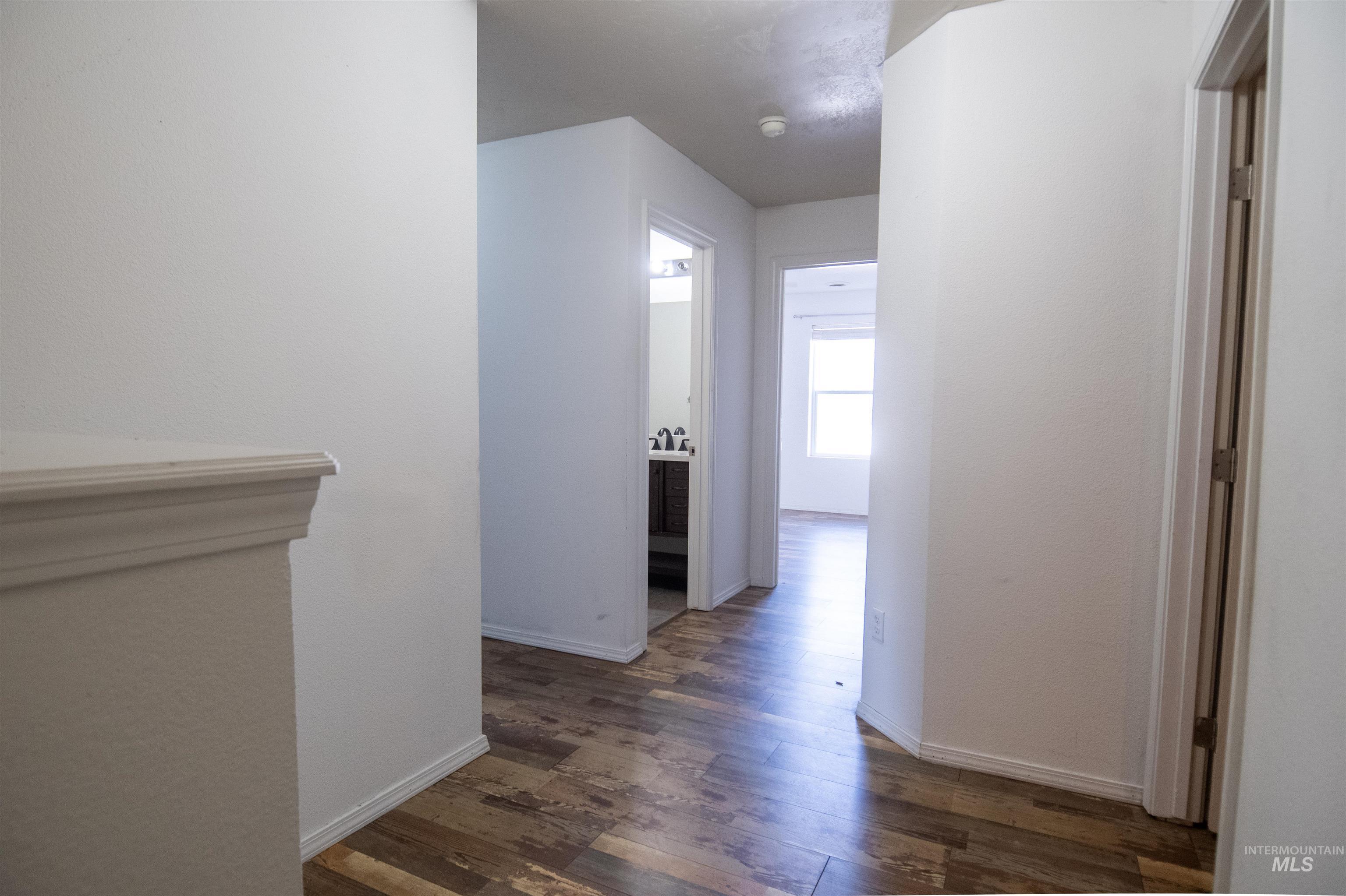 Corridor with dark wood-style flooring and baseboards