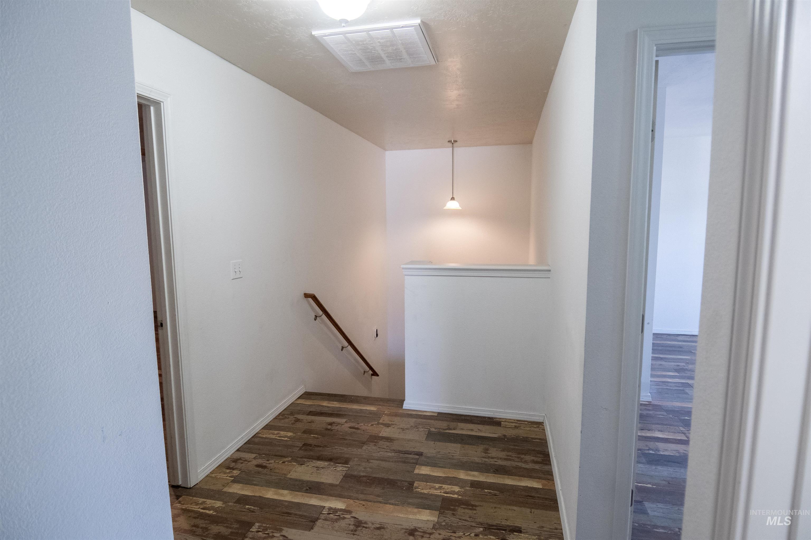 Corridor with an upstairs landing and dark wood-style floors