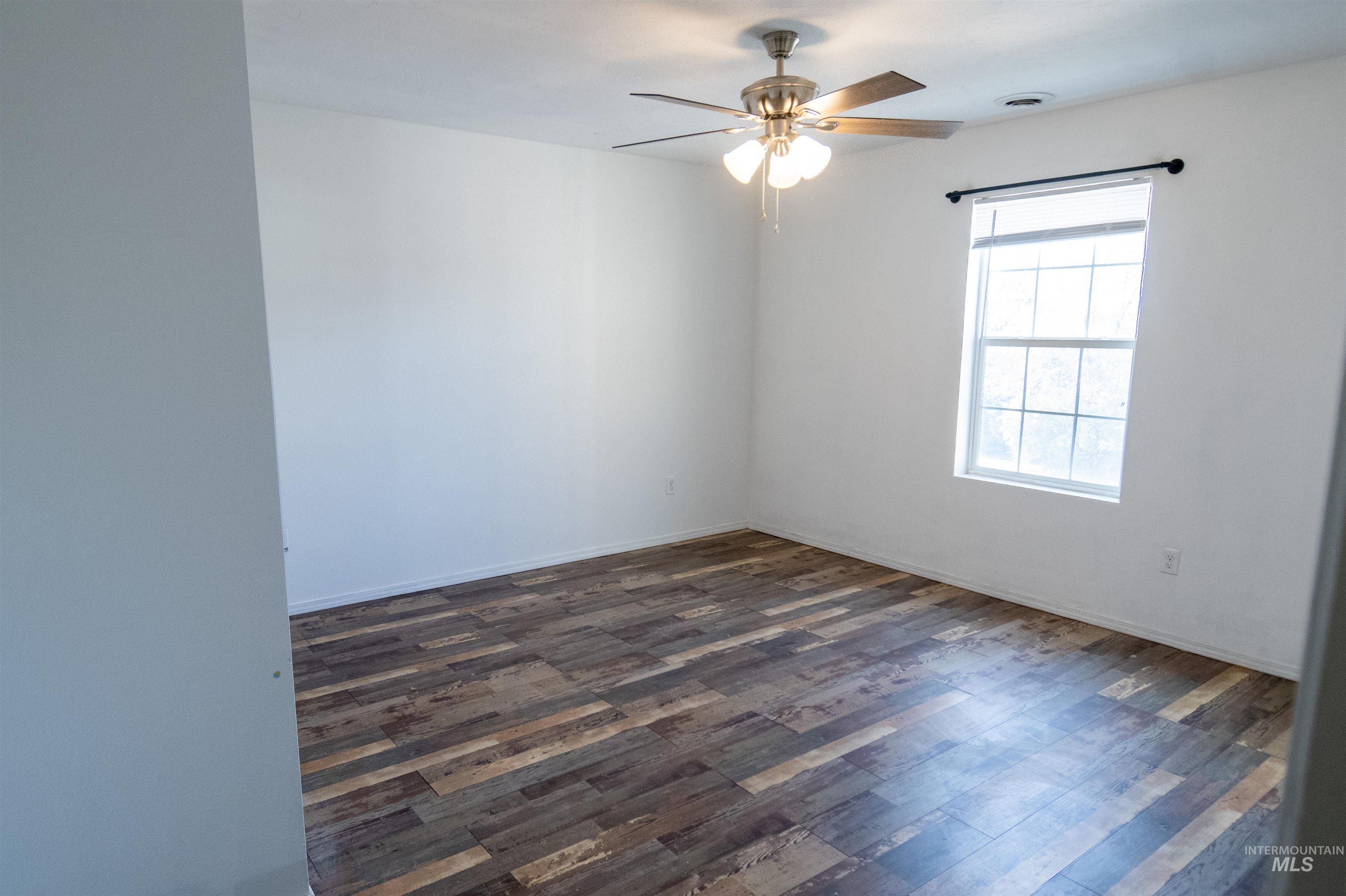 Empty room with dark wood finished floors and ceiling fan