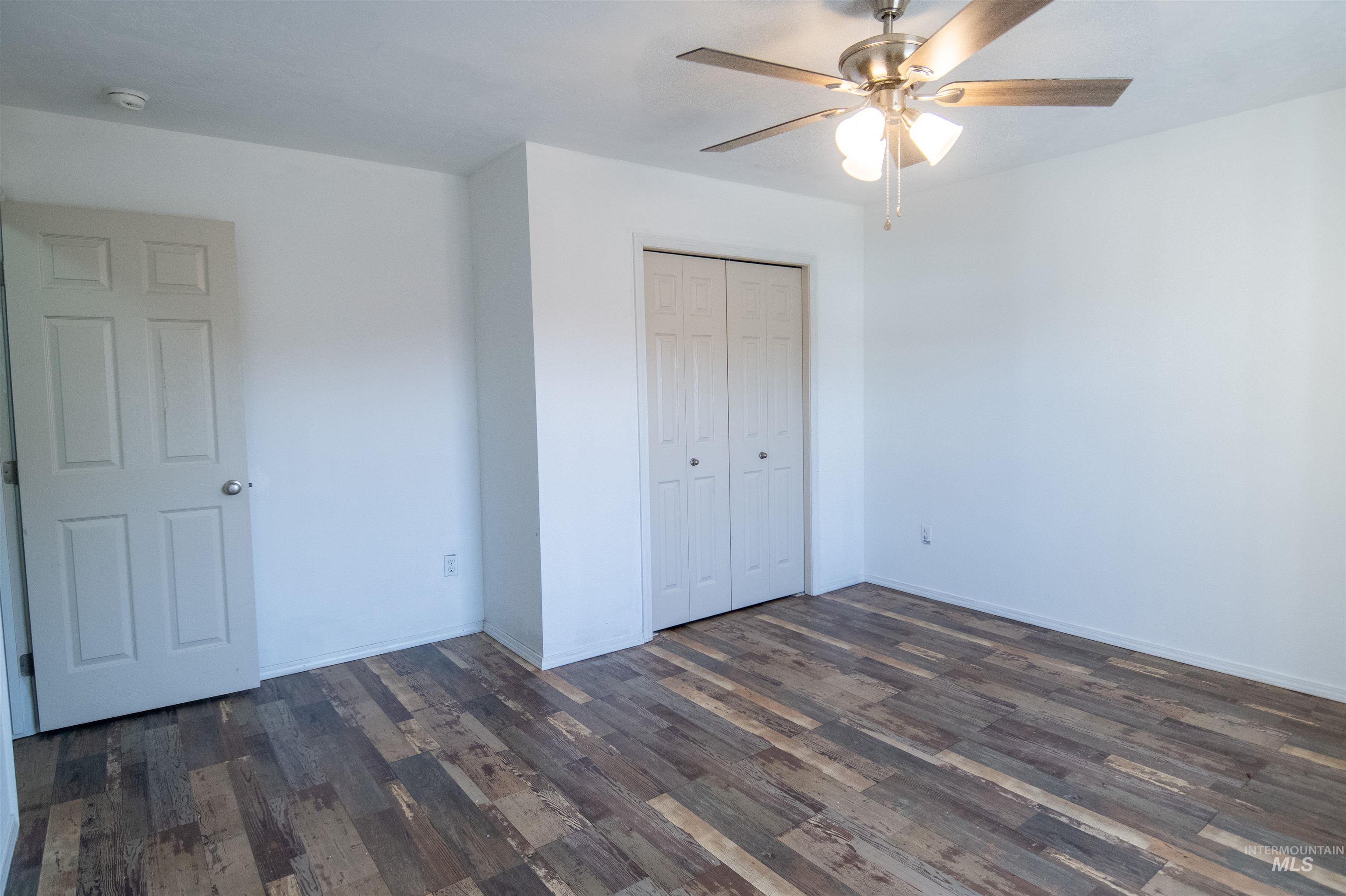 Unfurnished bedroom featuring dark wood-style floors, a closet, and ceiling fan