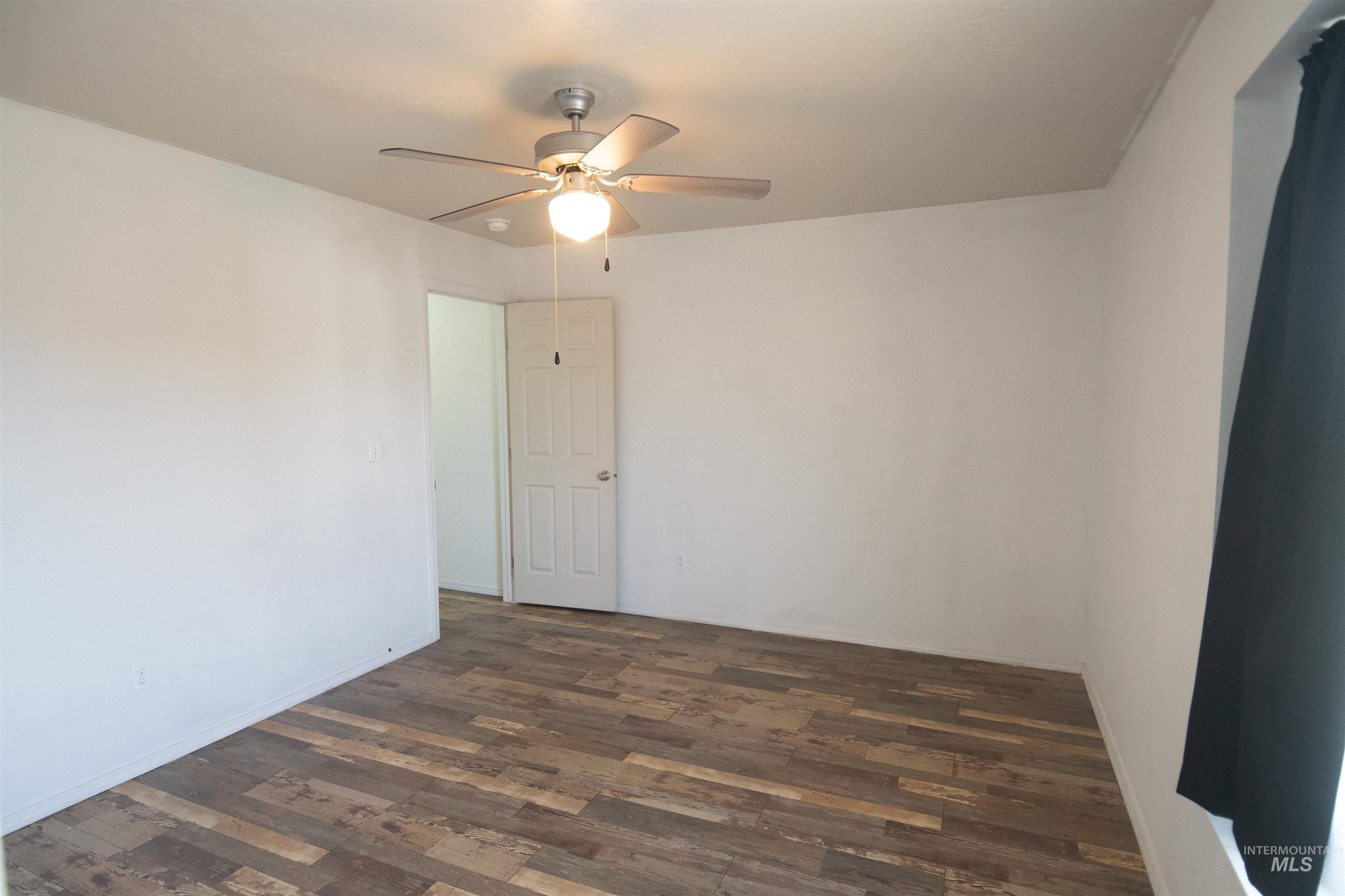 Spare room featuring dark wood-type flooring and a ceiling fan