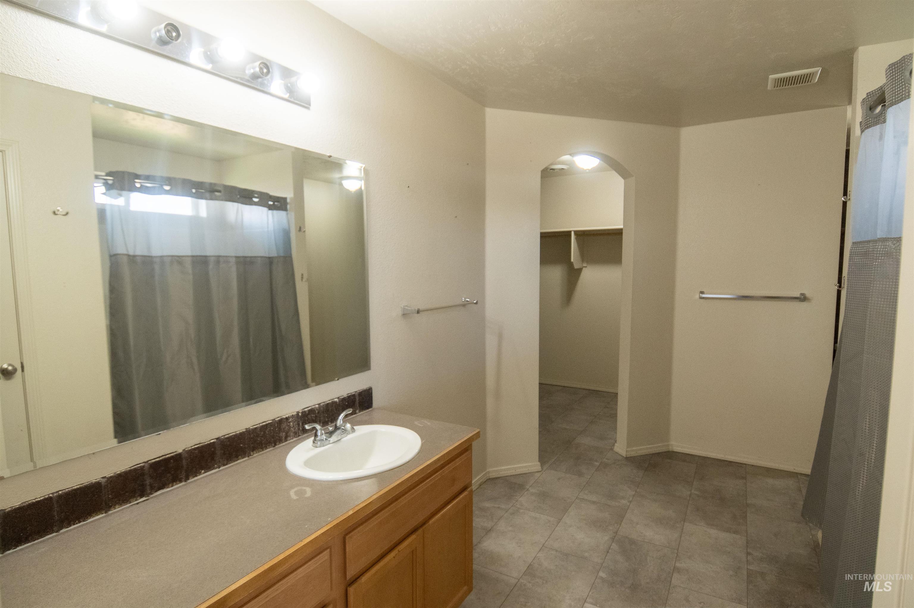 Bathroom featuring a spacious closet, a shower with shower curtain, and vanity